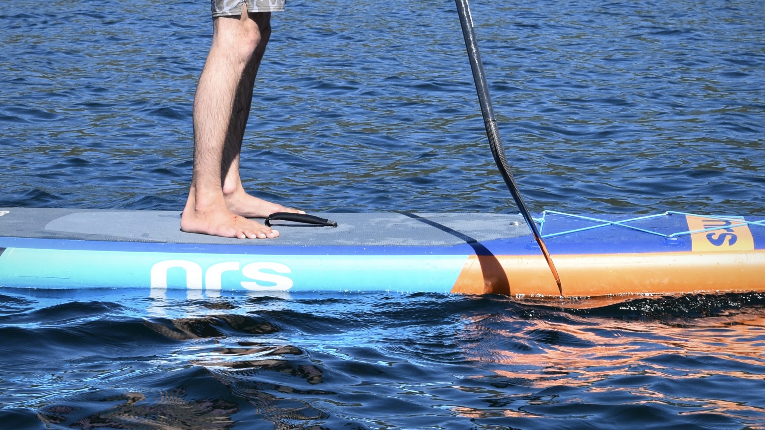 a close up view of a man paddle boarding on an alpine lake to demonstrate the SUP paddle offset