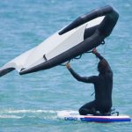 a man learning how to wing foil by starting on his knees on the slingshot ltf board in the water.