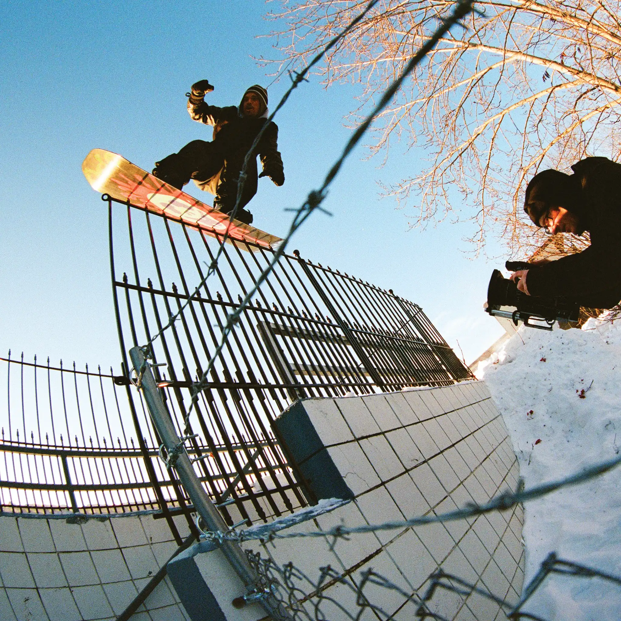 a snowboarder for ride snowboarders being filmed doing a rail slide 