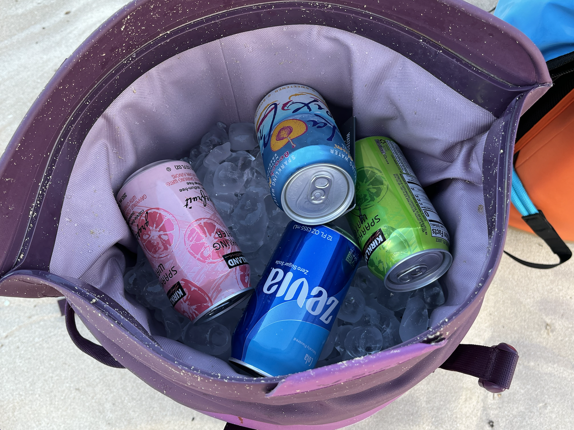 an assortment of drinks sitting on ice in an open backpack cooler