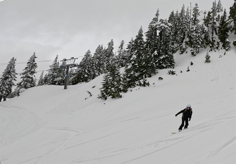 a snowboarder riding down a snowy slope while testing out the smith vantage mips helmet