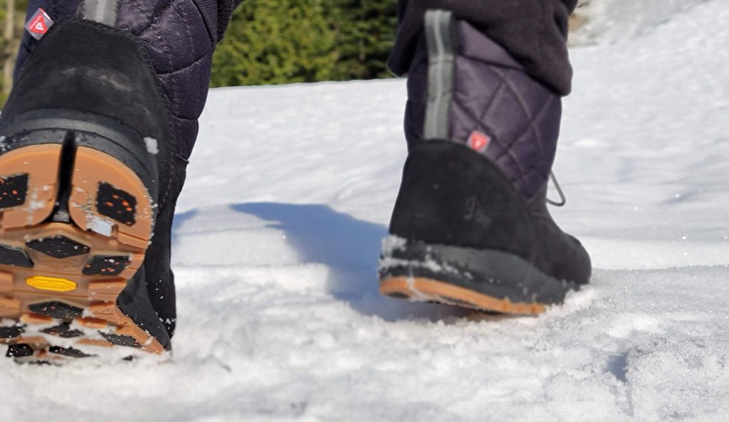 a shot of the vibram arctic grip outsoles on the danner cloud cap winter boots while walking in the snow