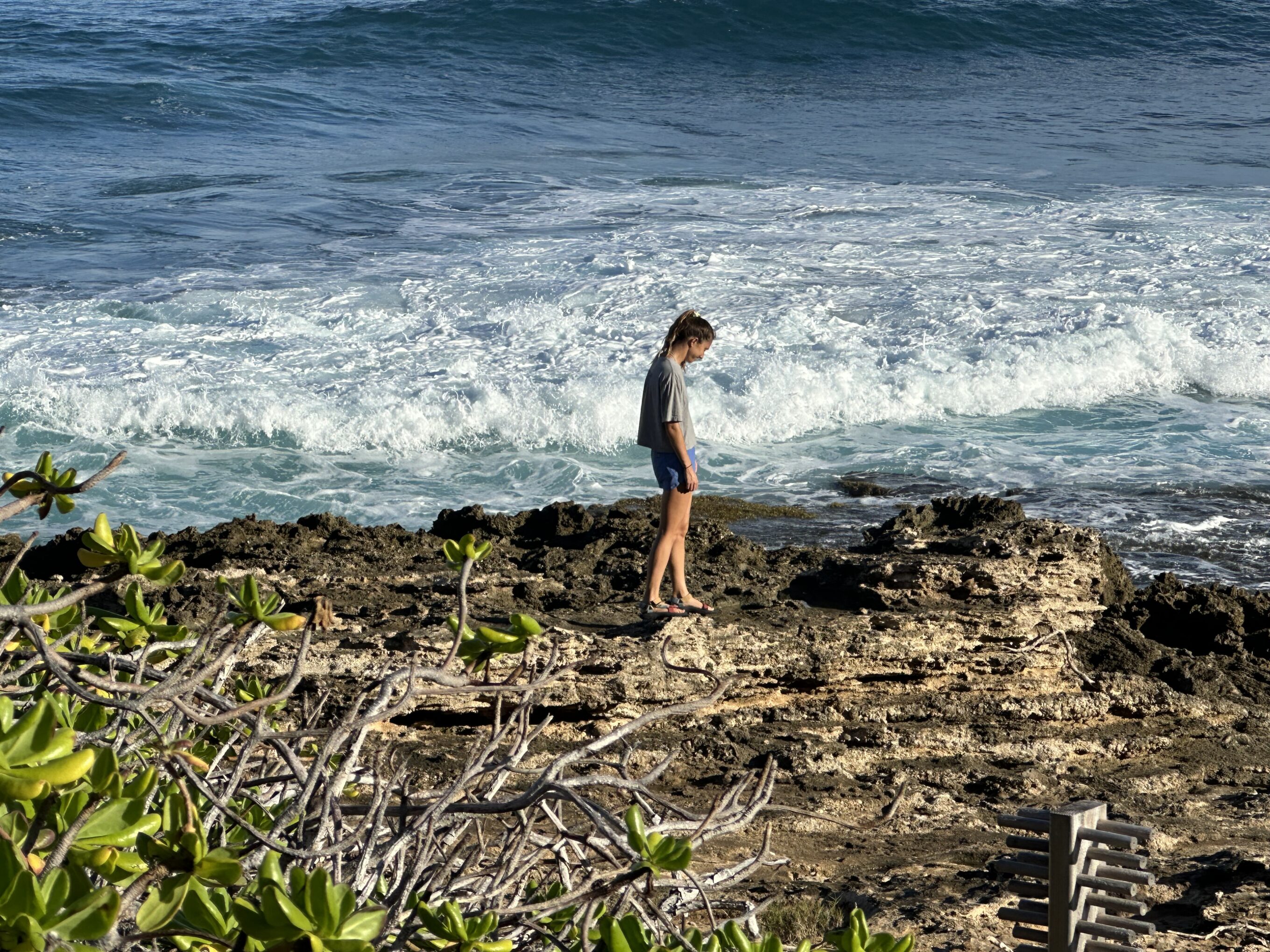 A woman stands by the shore in a pair of water shoes