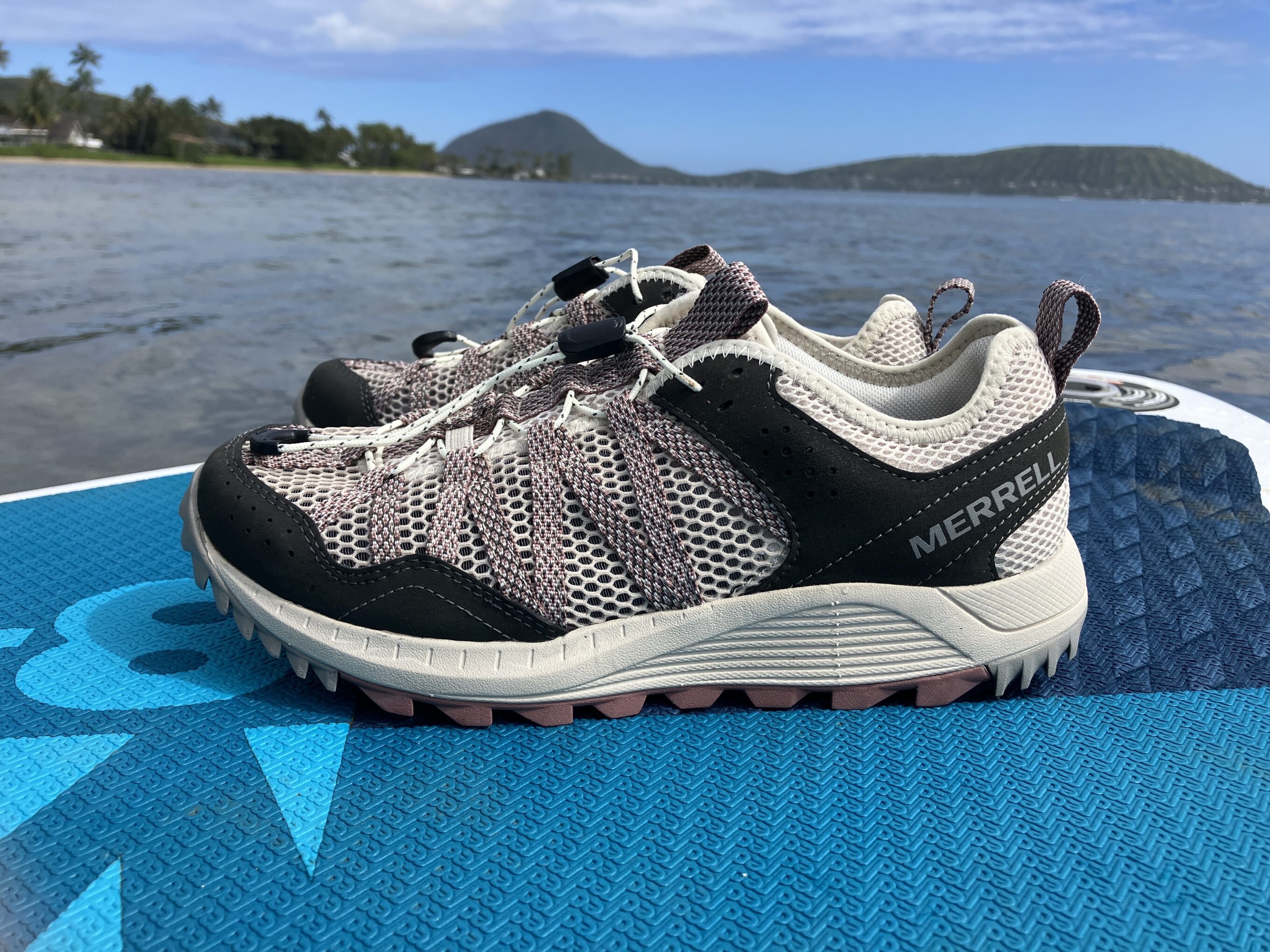 A pair of Merrell water shoes on a stand up paddleboard in the middle of the water