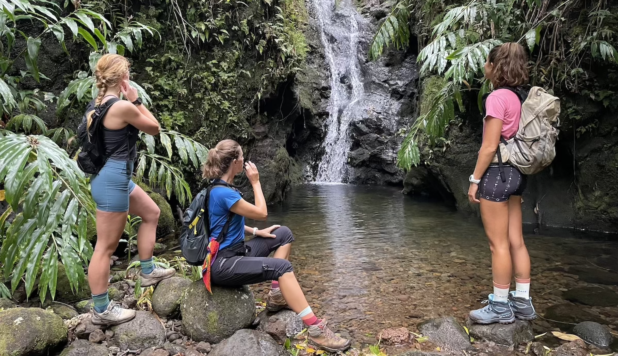 a group of women stand looking at a waterfall