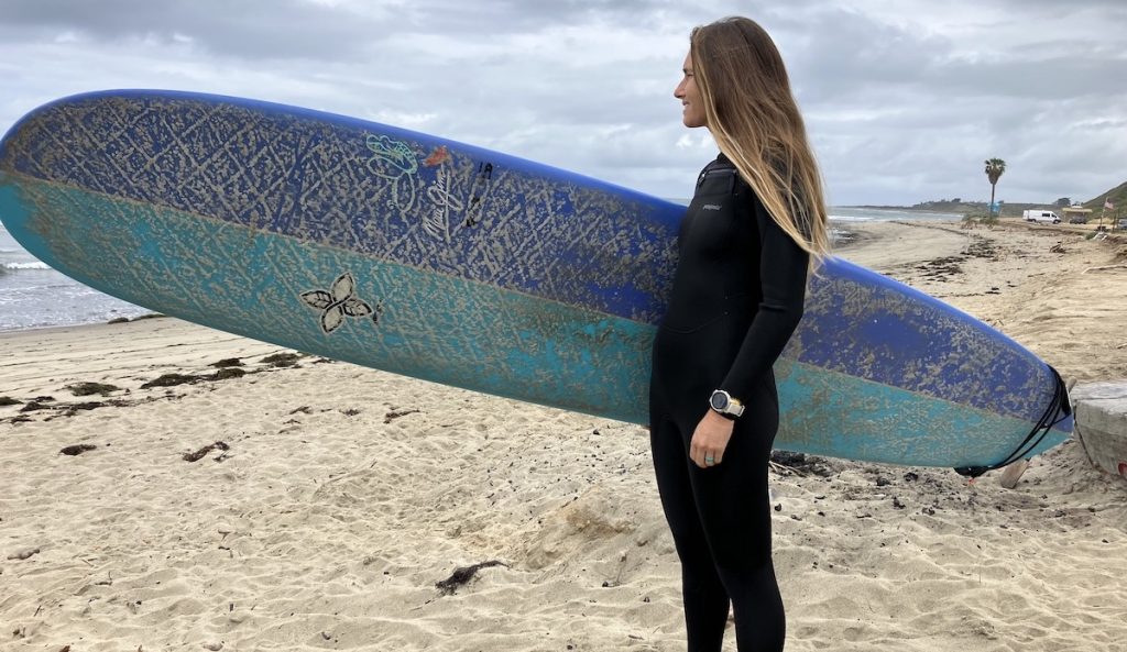 women in a patagonia wetsuit holding a surfboard
