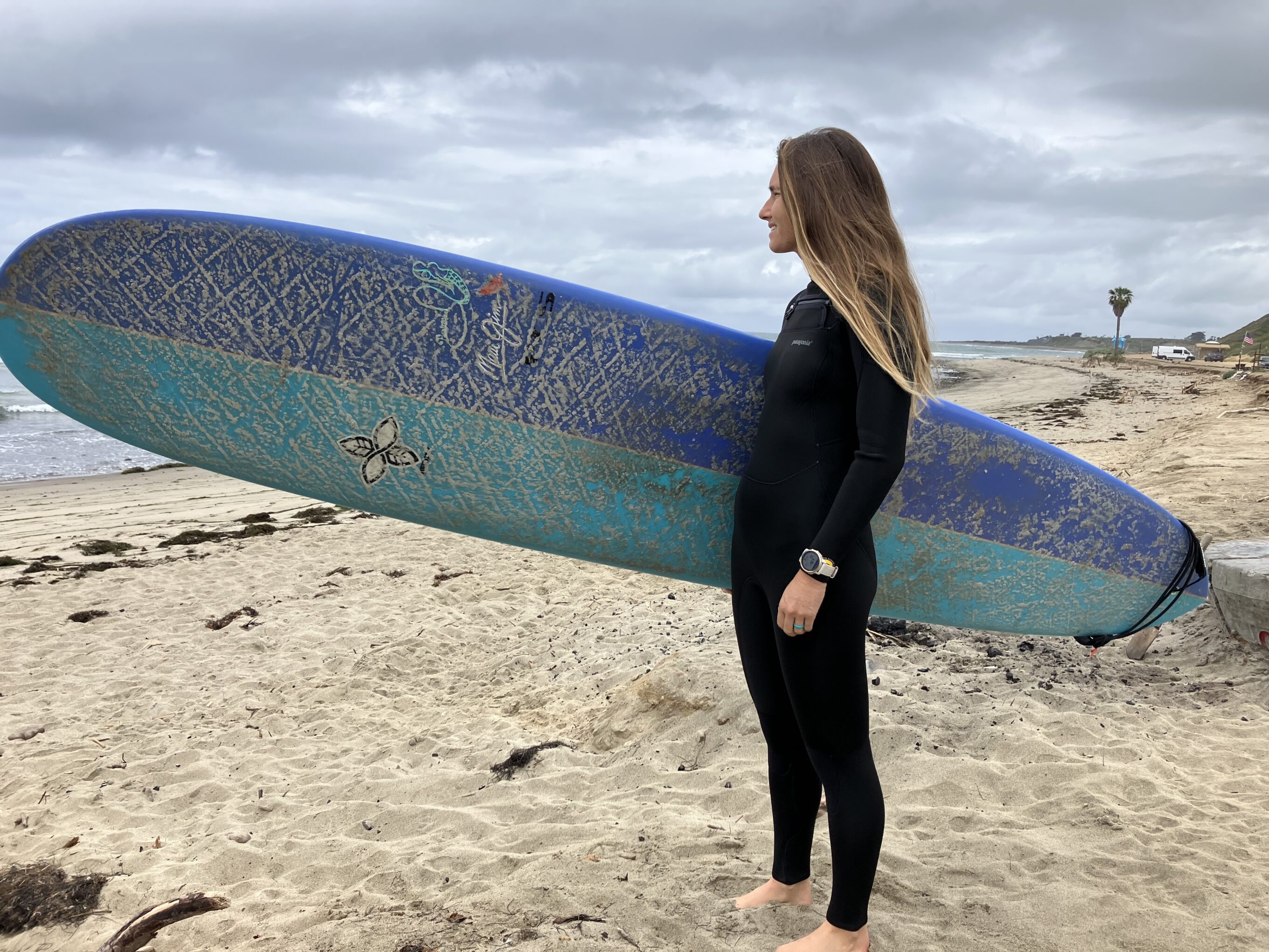 women in a wetsuit holding a surboard