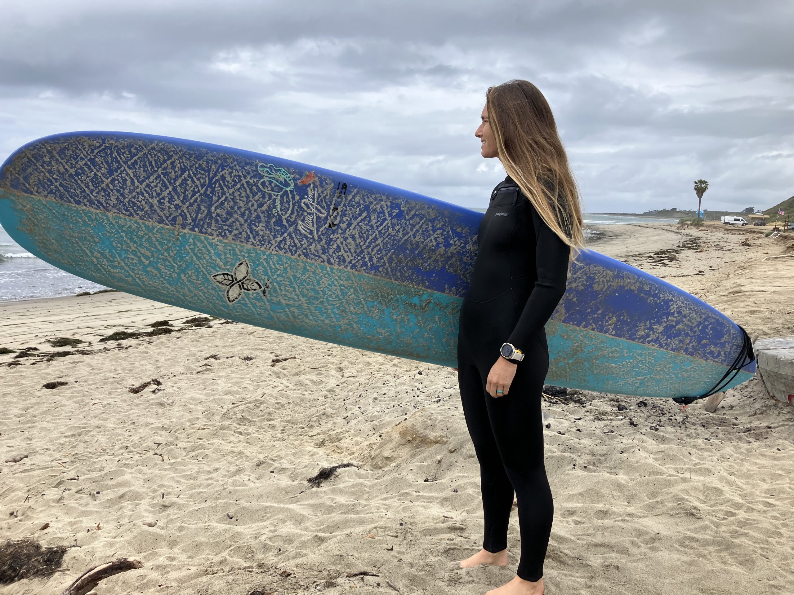 women in a wetsuit holding a surboard