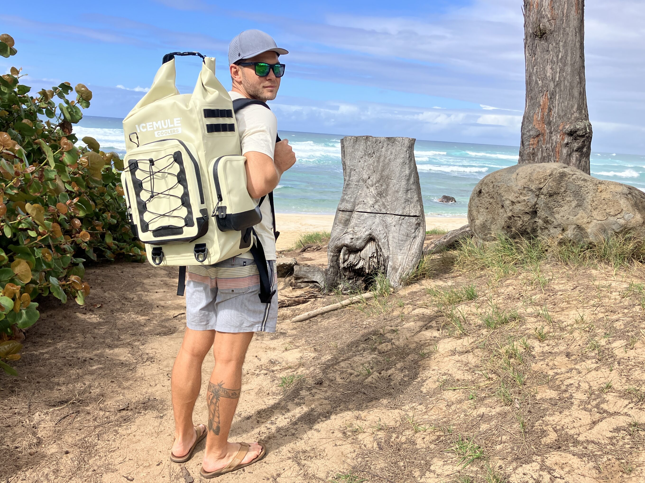 man holding a backpack cooler at the beach