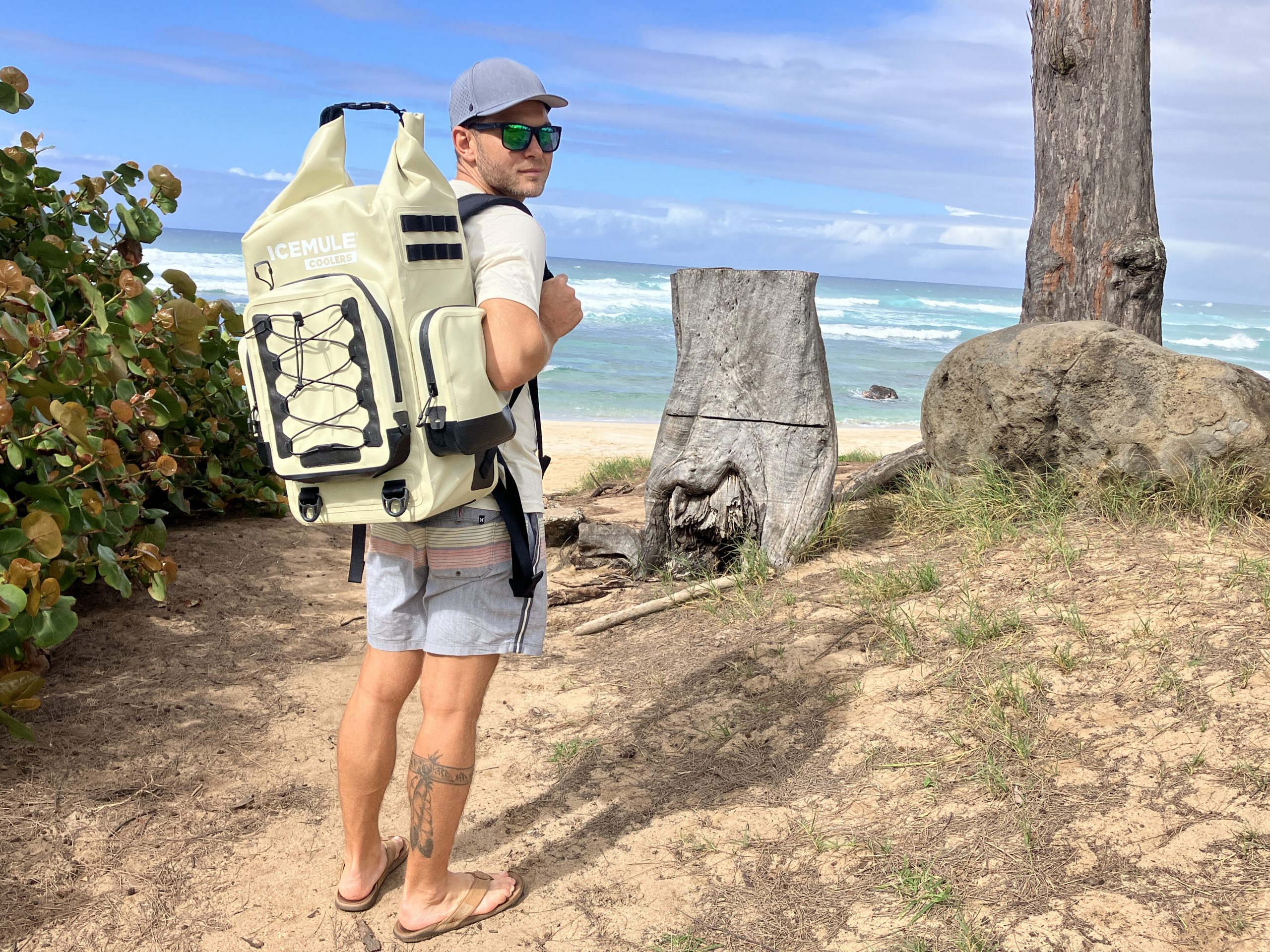man holding a backpack cooler at the beach