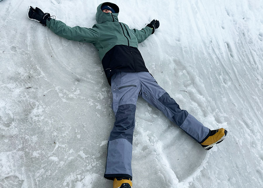making a snow angel in slushy conditions to test outerwear