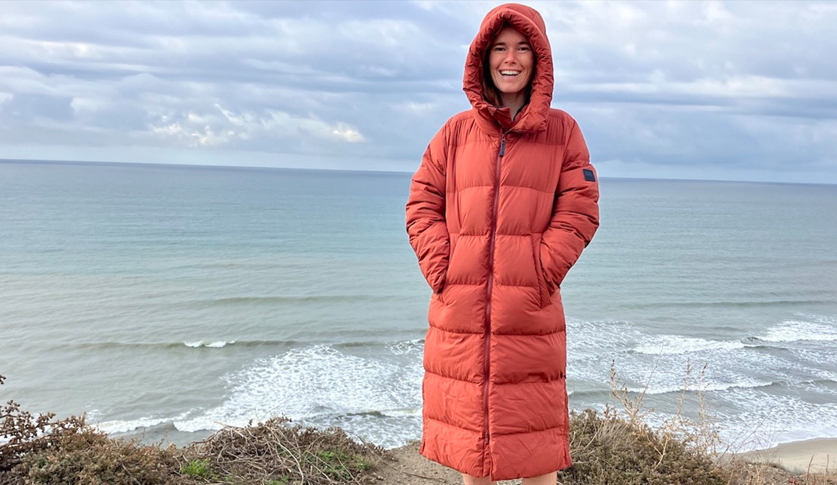 a woman wearing the Outdoor Research Coze Down Parka on a cliff above the beach