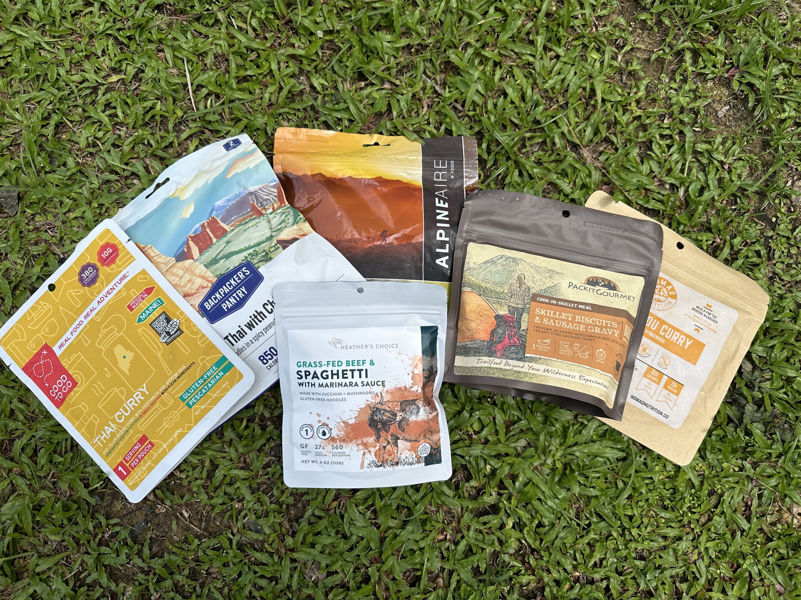 a variety of backpacking meals sitting on the grass