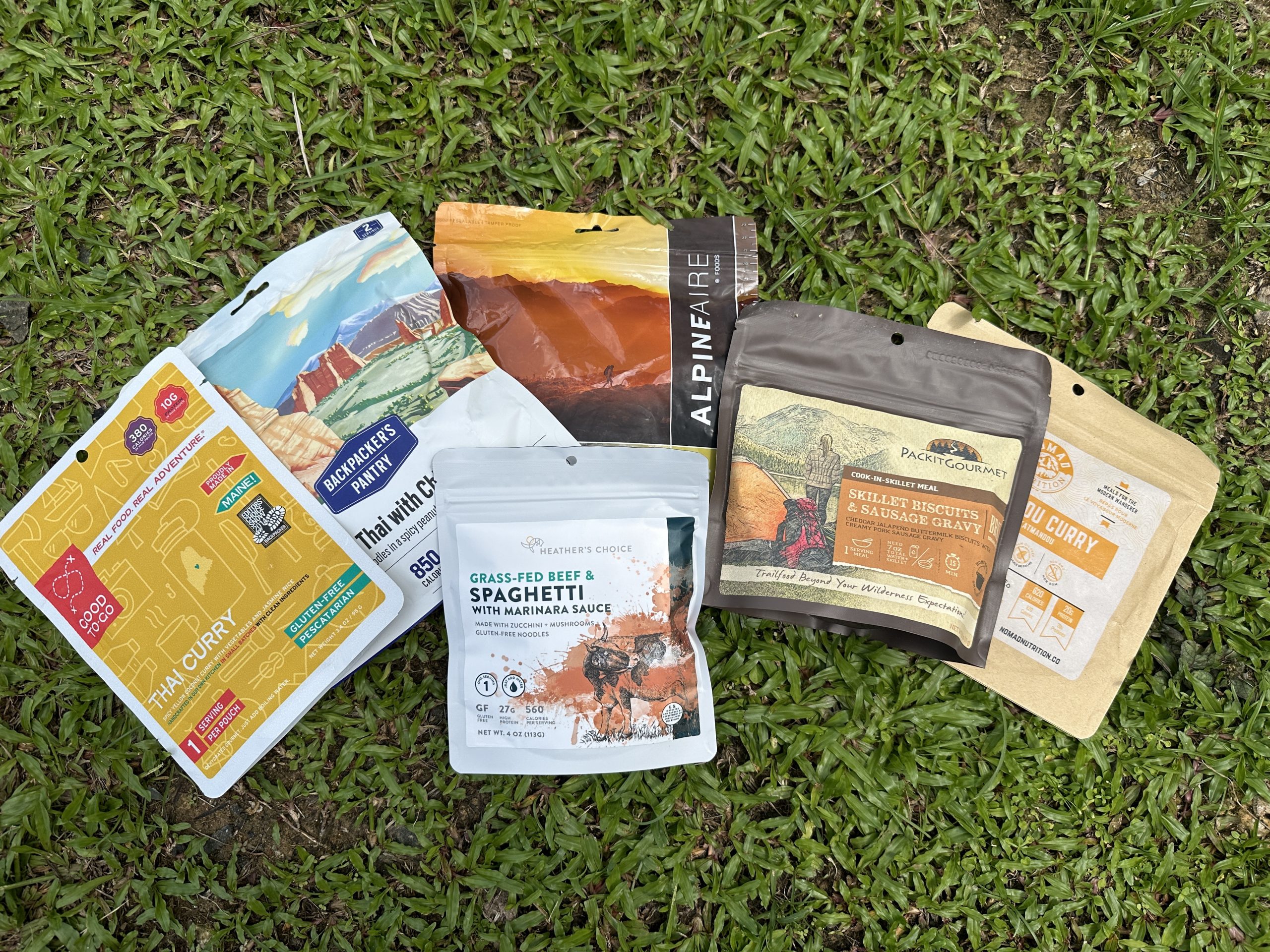 a variety of backpacking meals sitting on the grass