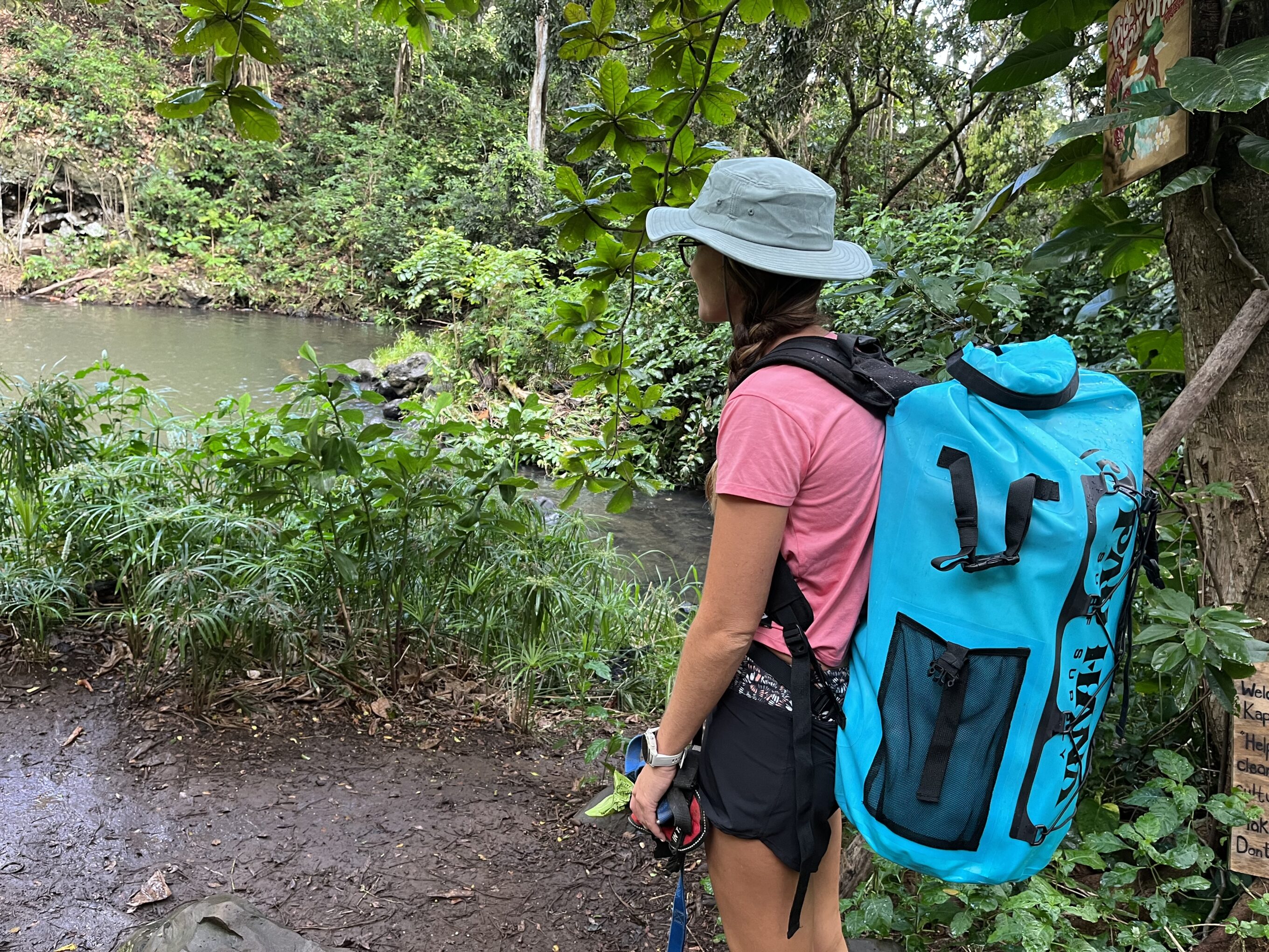 woman wearing a hat and an inflatable paddleboard backpack in the forest