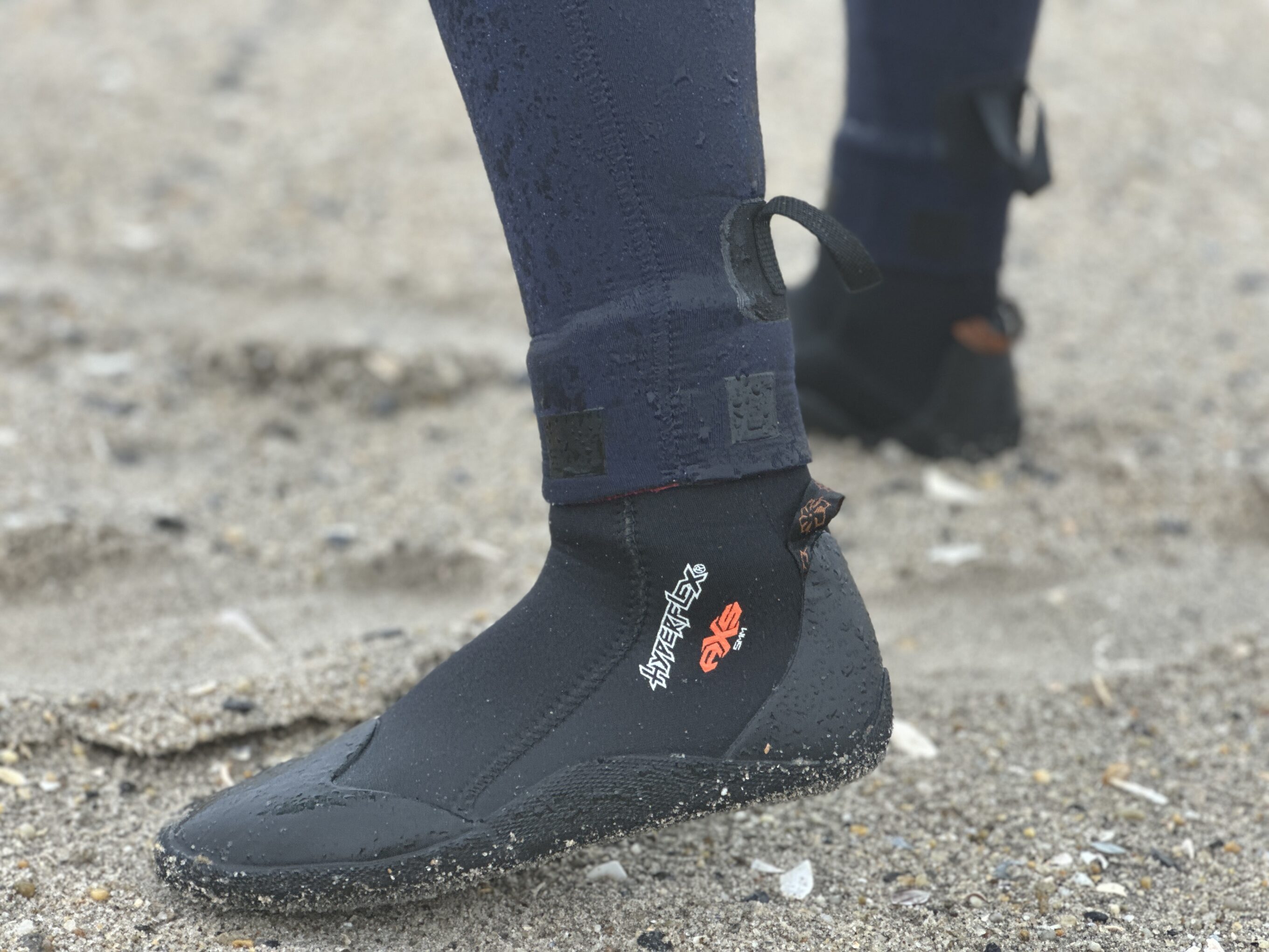 a women's feet in surf booties and a wetsuit at the