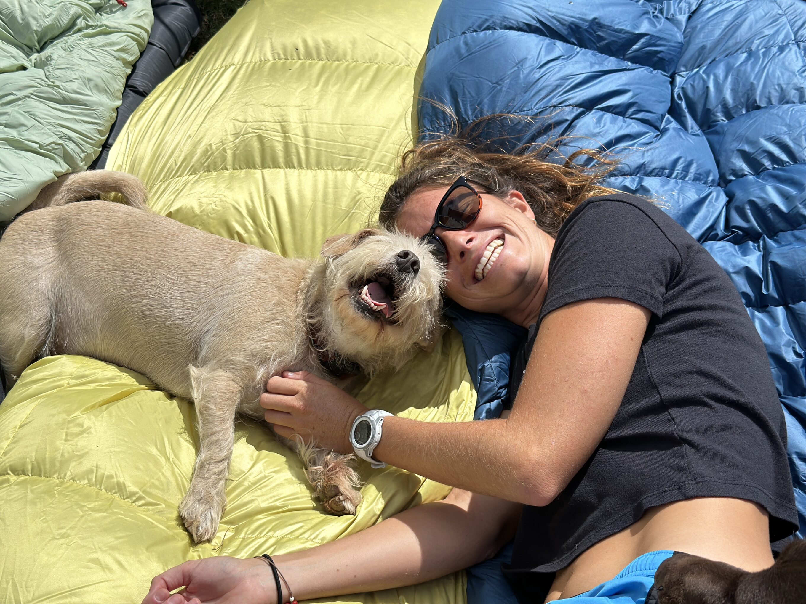 a woman and a dog laying on sleeping bags