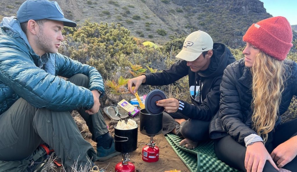 three friends making meals using backpacking stoves