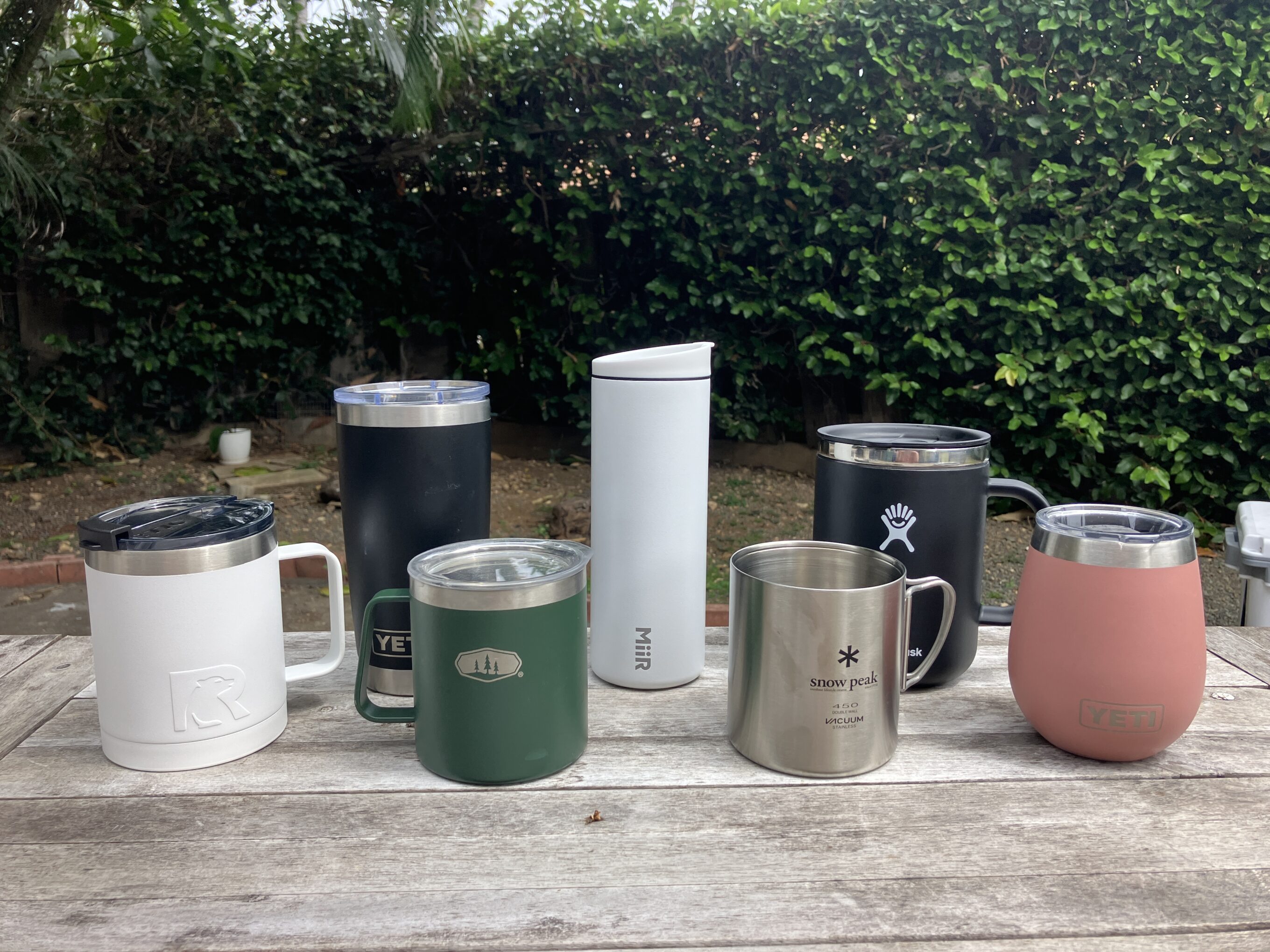 an assortment of the best insulated coffee mugs sitting on a wooden table