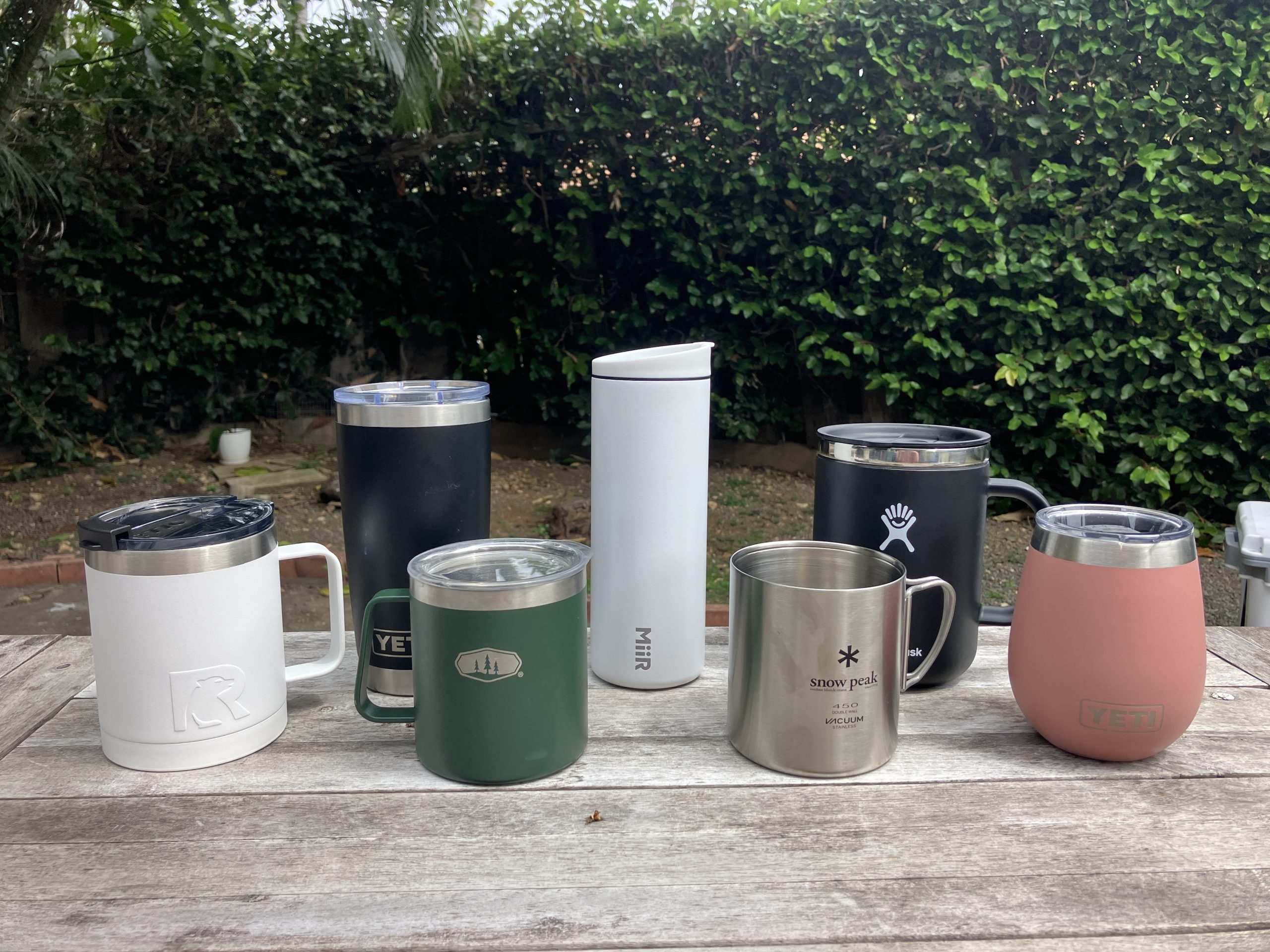 an assortment of the best insulated coffee mugs sitting on a wooden table