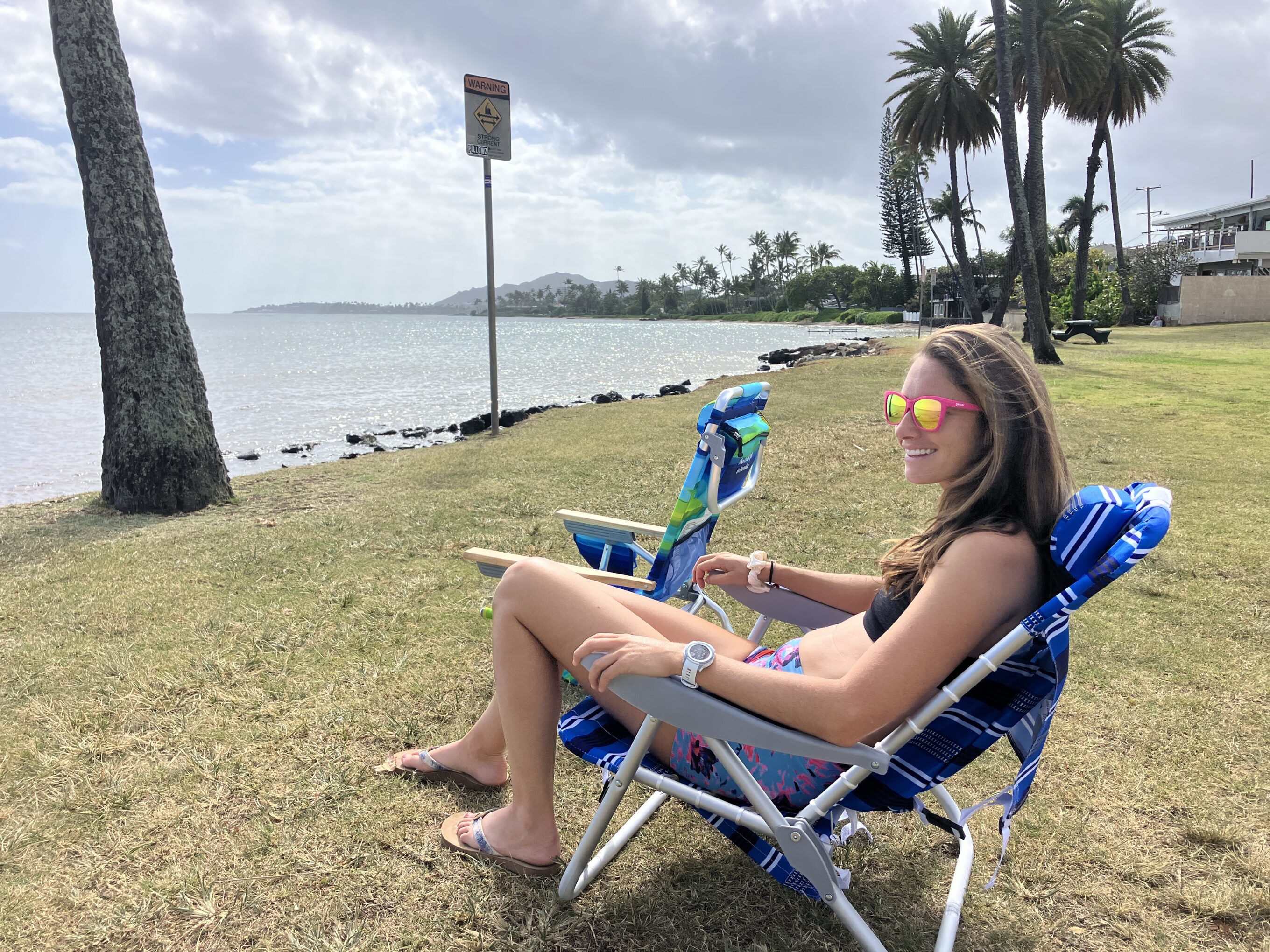 a girl sitting in a beach chair at the beach