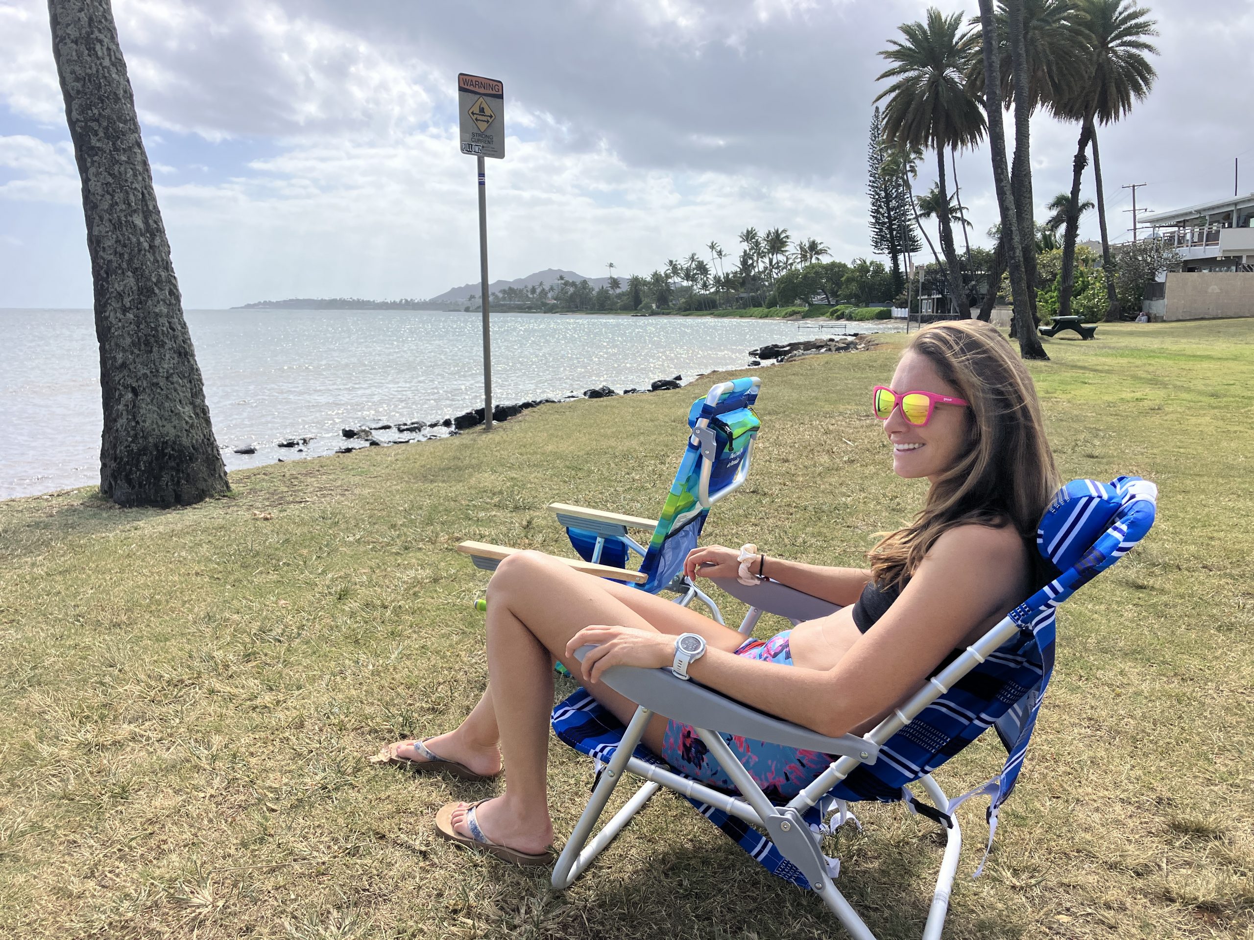 a girl sitting in a beach chair at the beach
