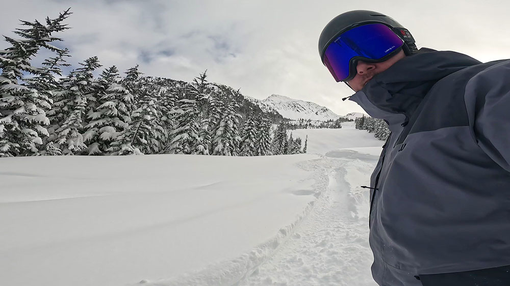 A snowboarder riding down the mountain wearing the Dragon NFX Mag Infrared goggles