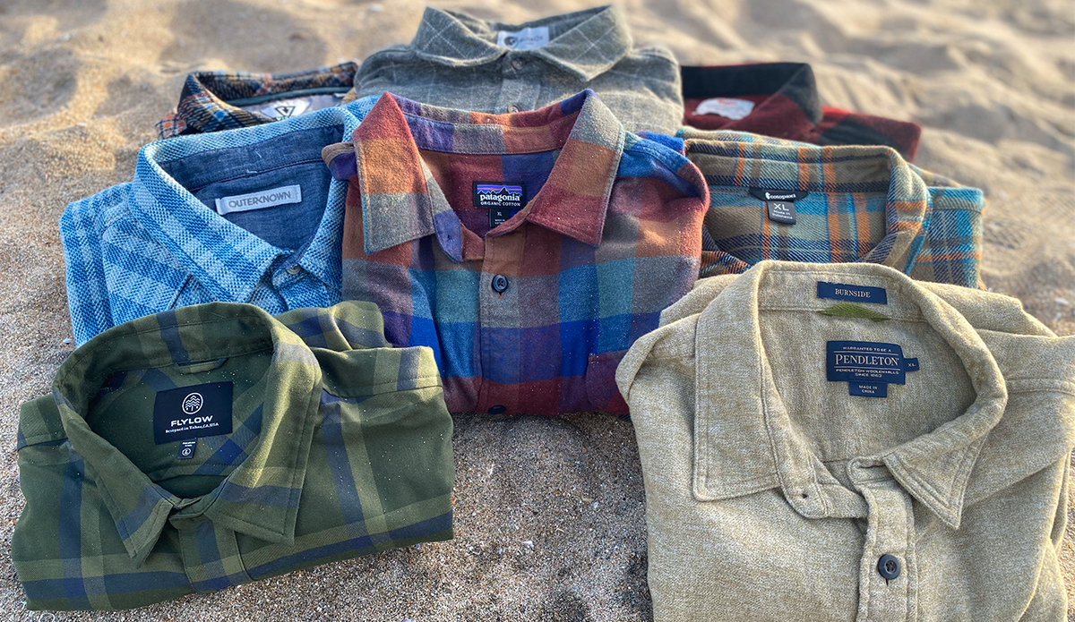 a pile of flannel shirts sitting on the beach