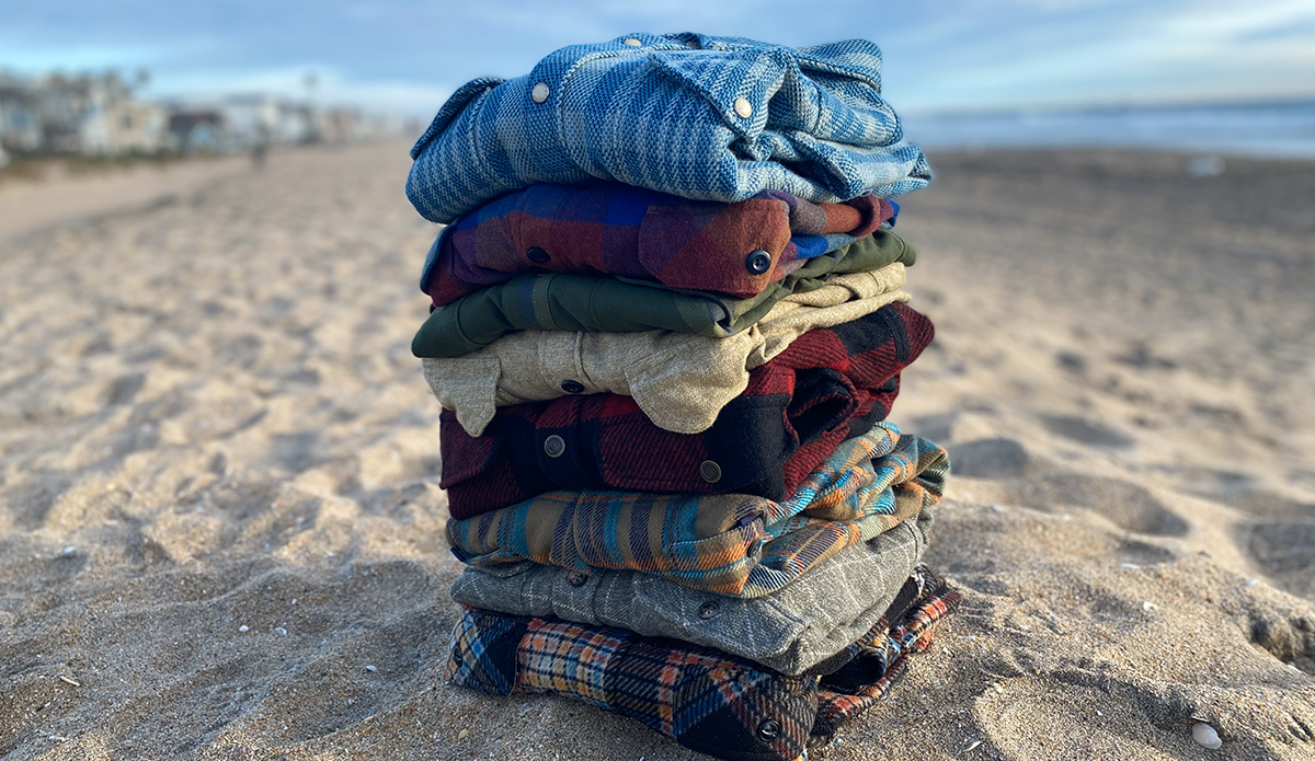 a pile of flannel shirts on the beach.