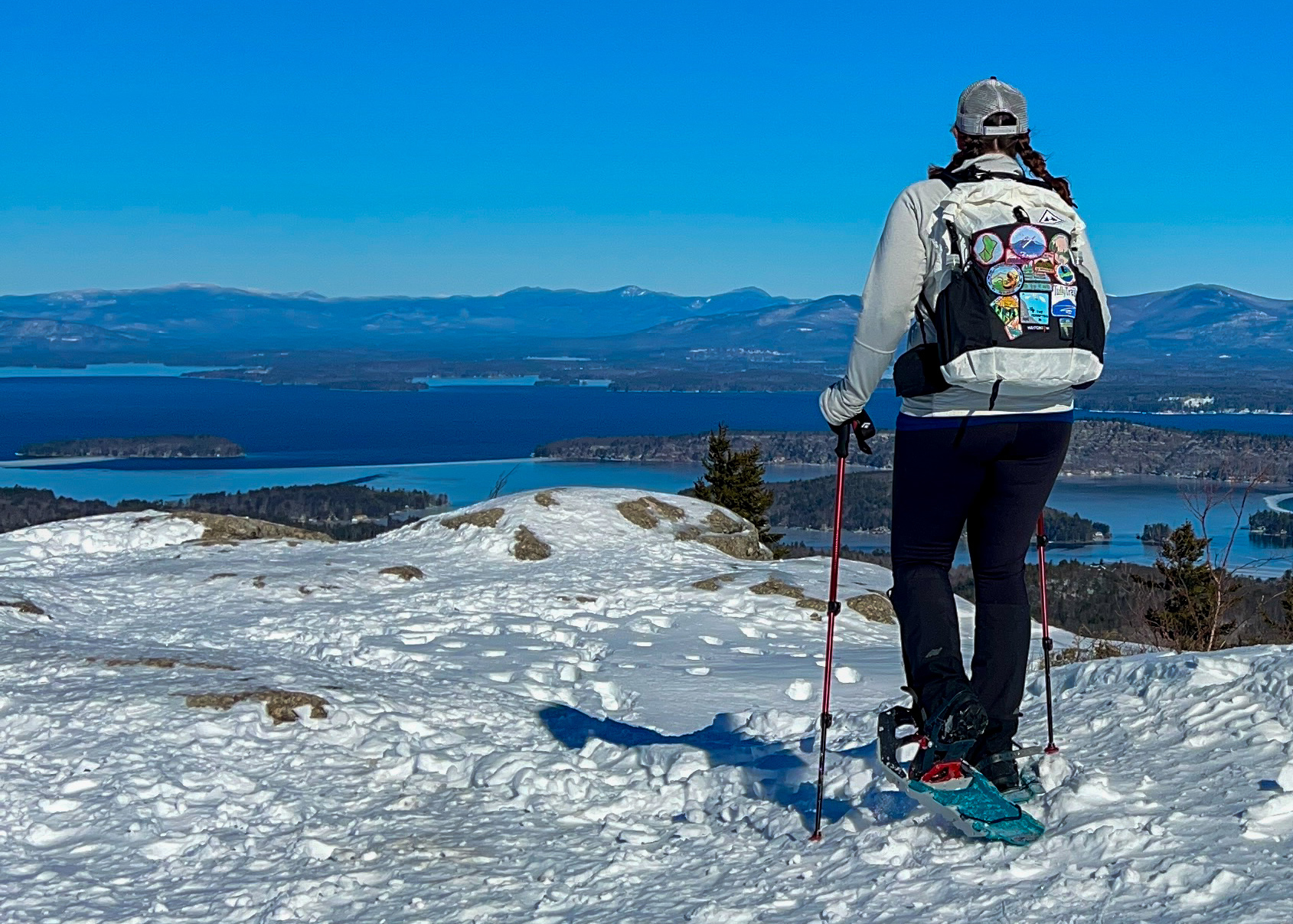 a woman tests snowshoes above a series of lakes
