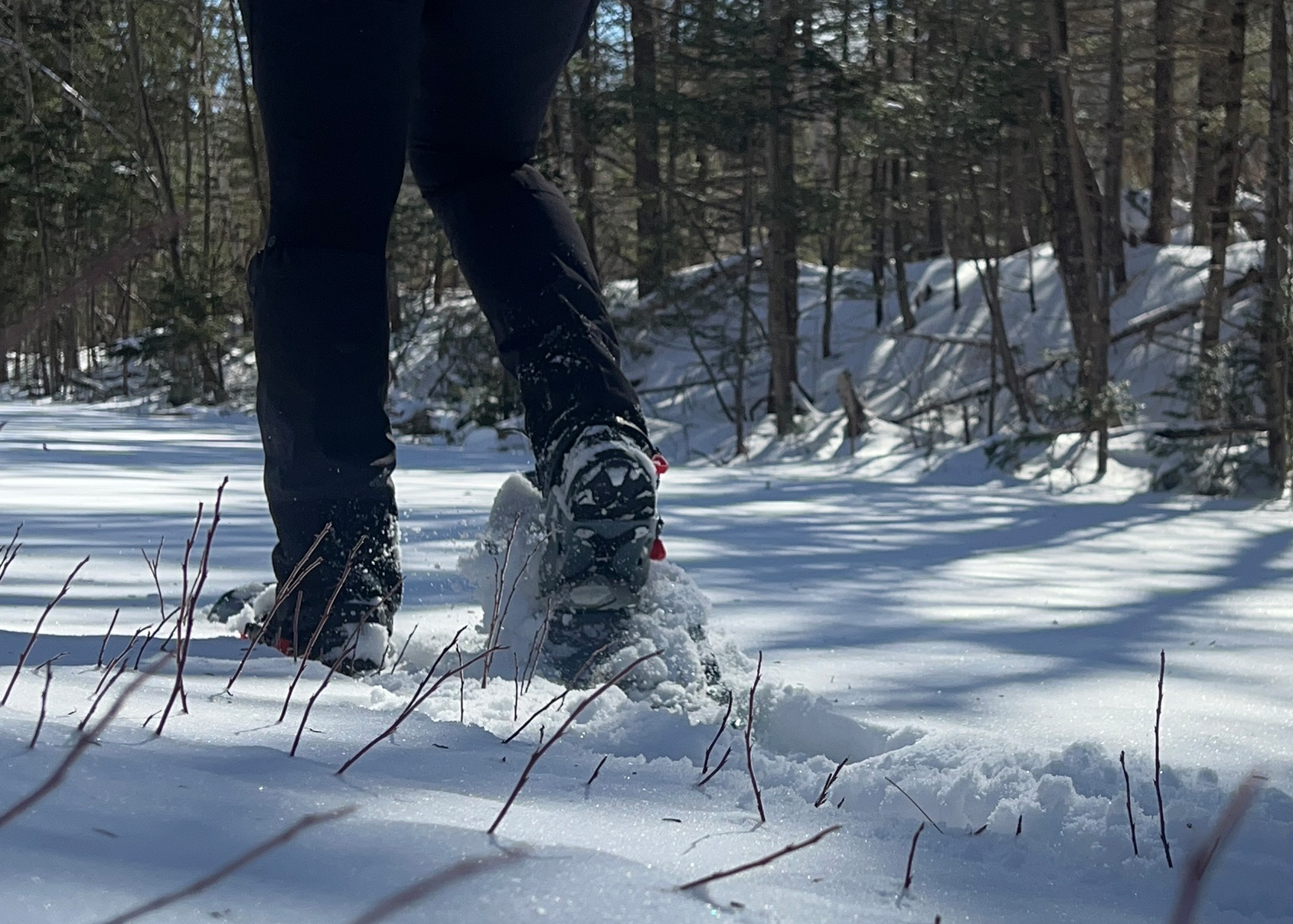 a woman using a pair of snowshoes on a flat trail