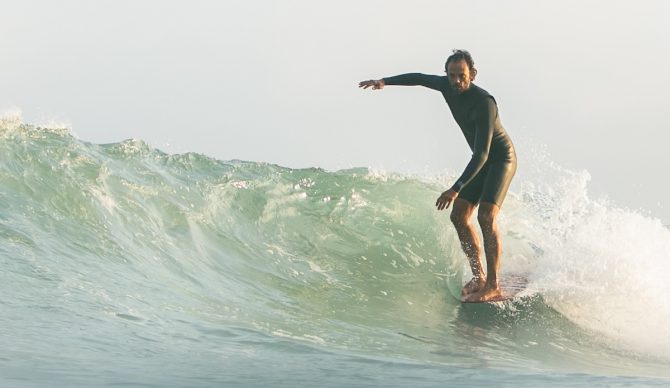 Man noseriding a longboard in a springsuit wetsuit