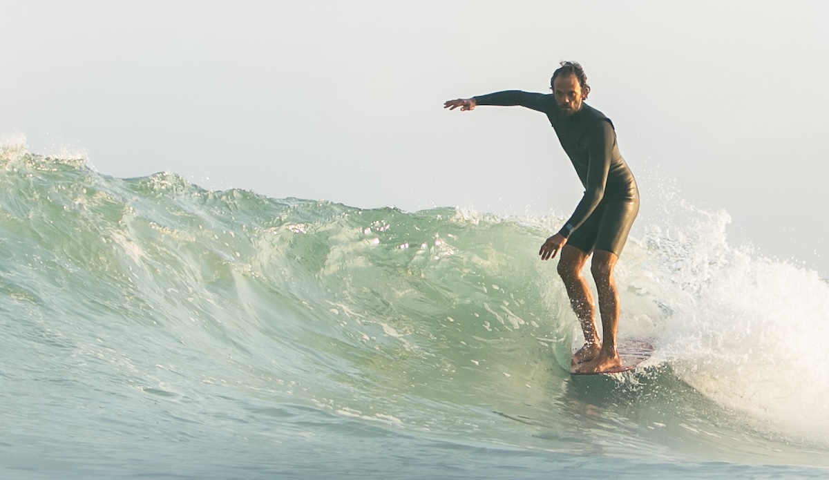Man noseriding a longboard in a springsuit wetsuit