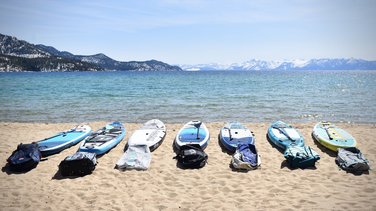 a bunch of inflatable stand up paddle boards lined up on a beach