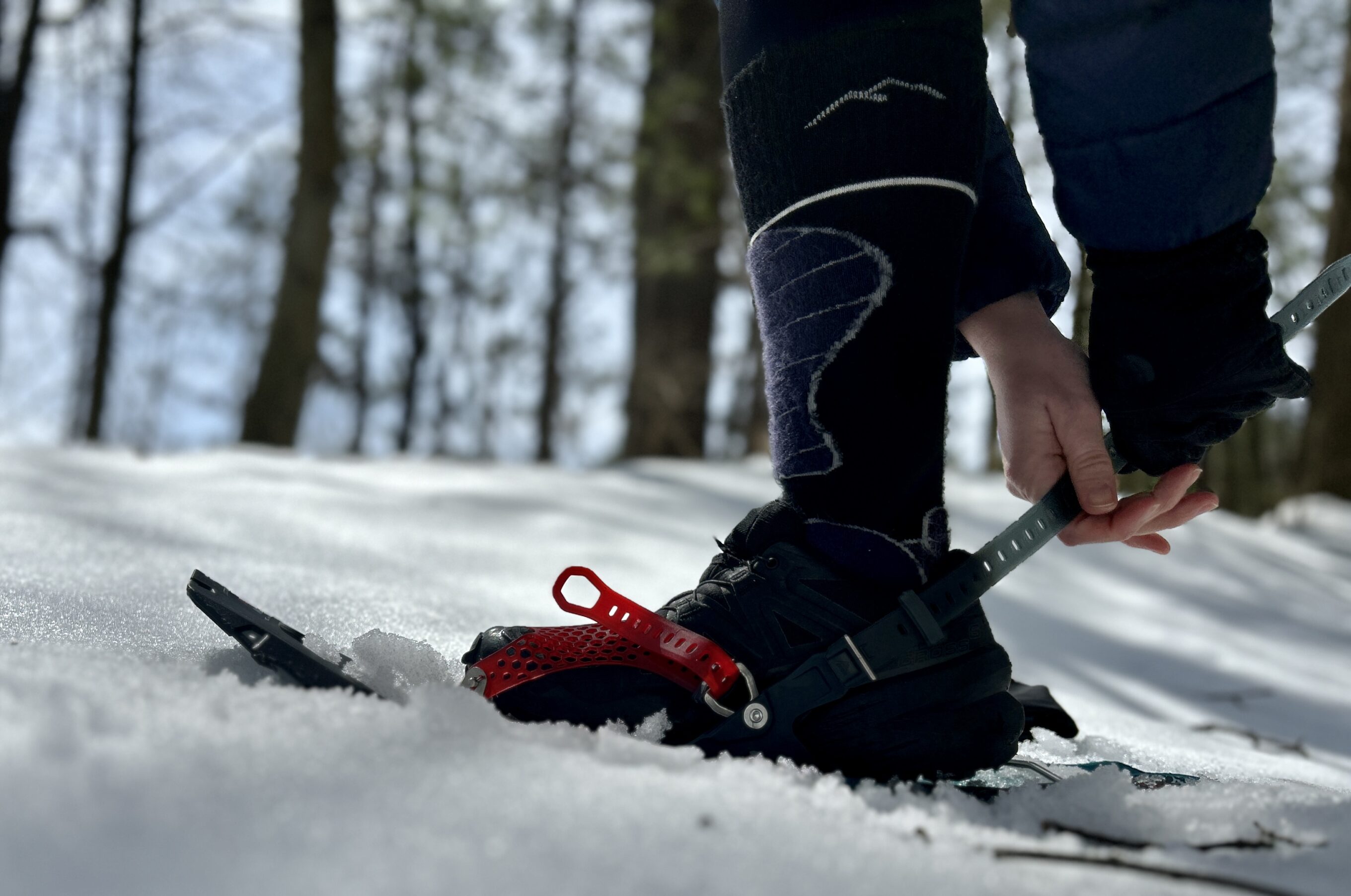 A woman adjusts the binding on the MSR Revo Ascent snowshoes