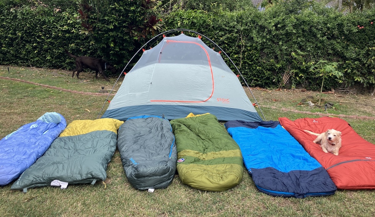 a bunch of camping sleeping bags lines up in front of a tent