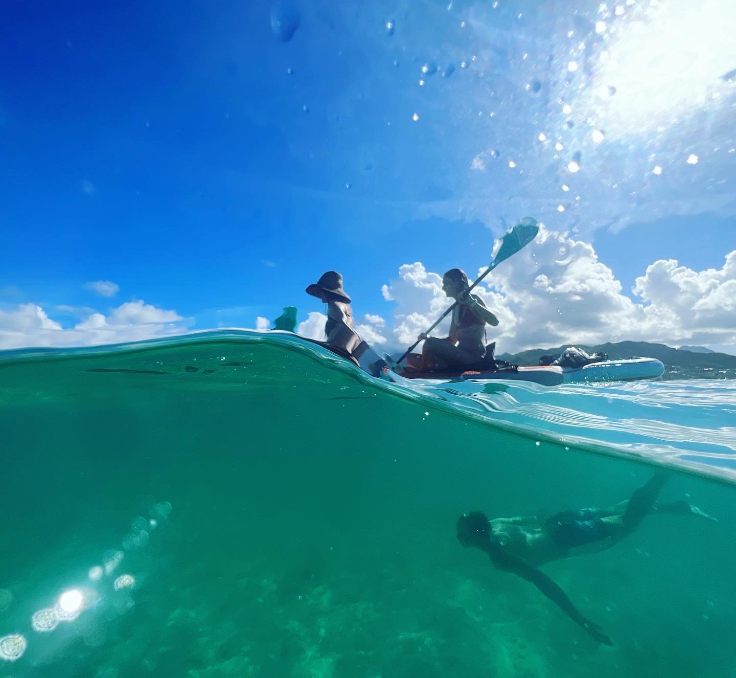 an underwater photo of kayakers with someone swimming below