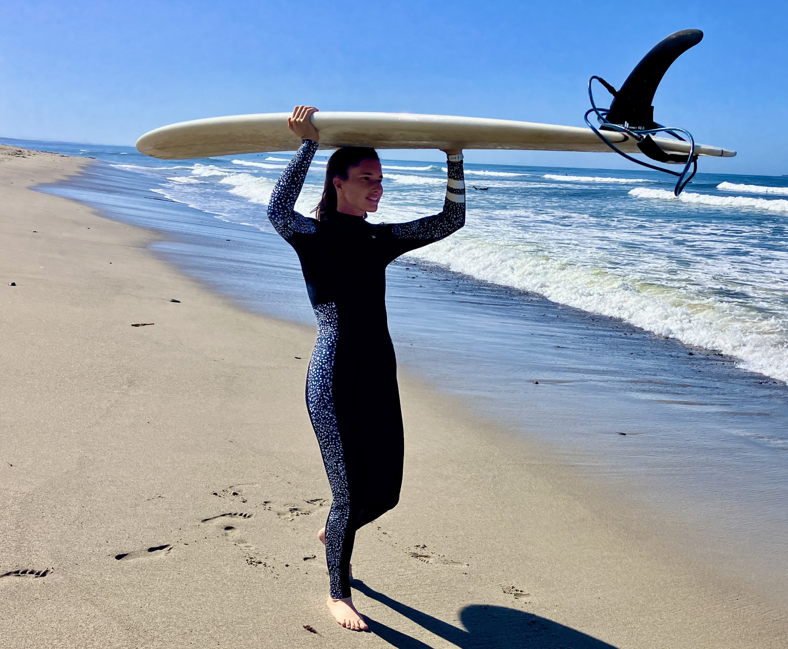 a woman carrying a surfboard at the beach