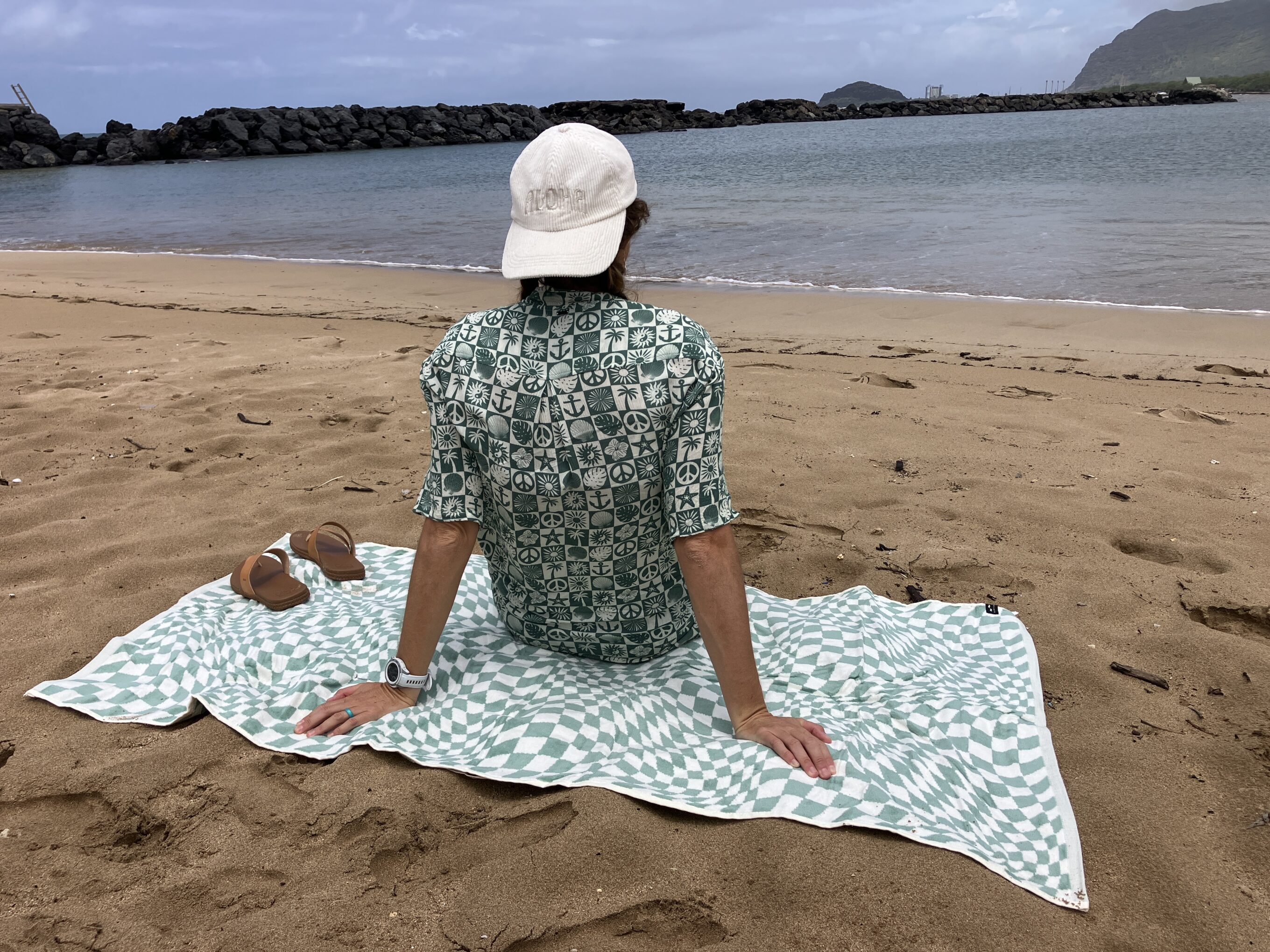a girl sitting on a towel at the beach