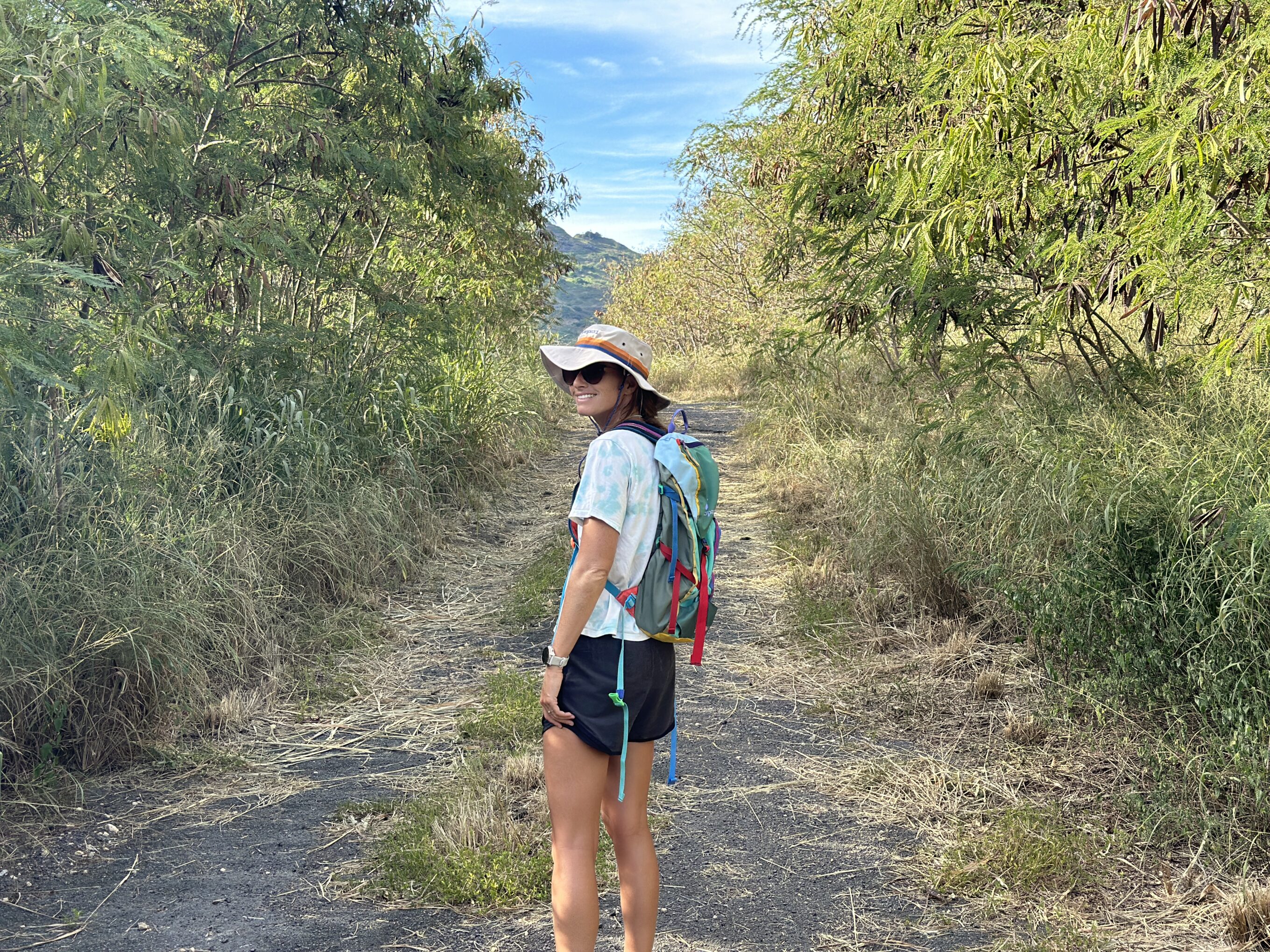 a woman hiking wearing a hat and hiking backpack