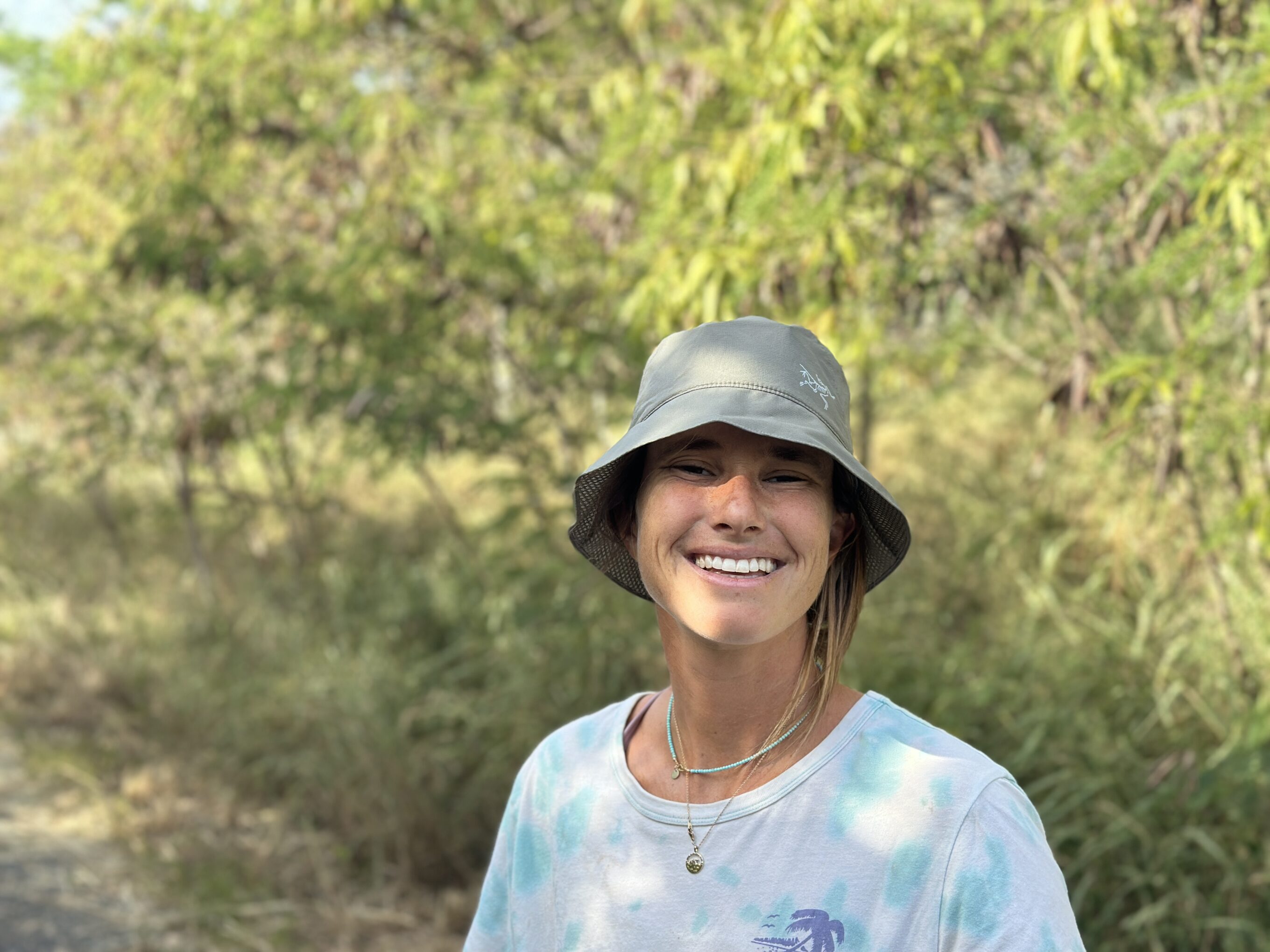 a woman smiling wearing a sun hat
