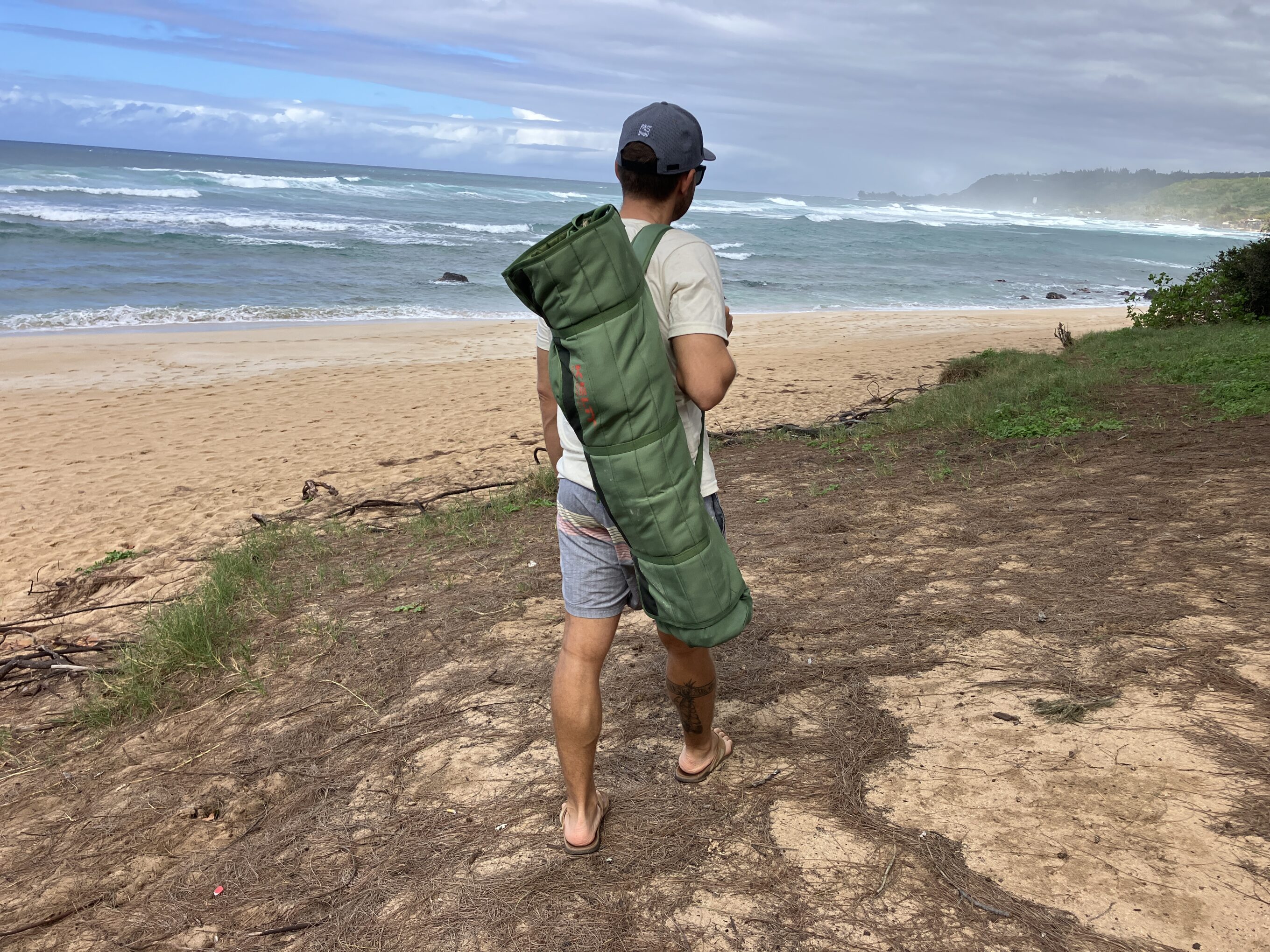 a man walking with a folded up camping chair