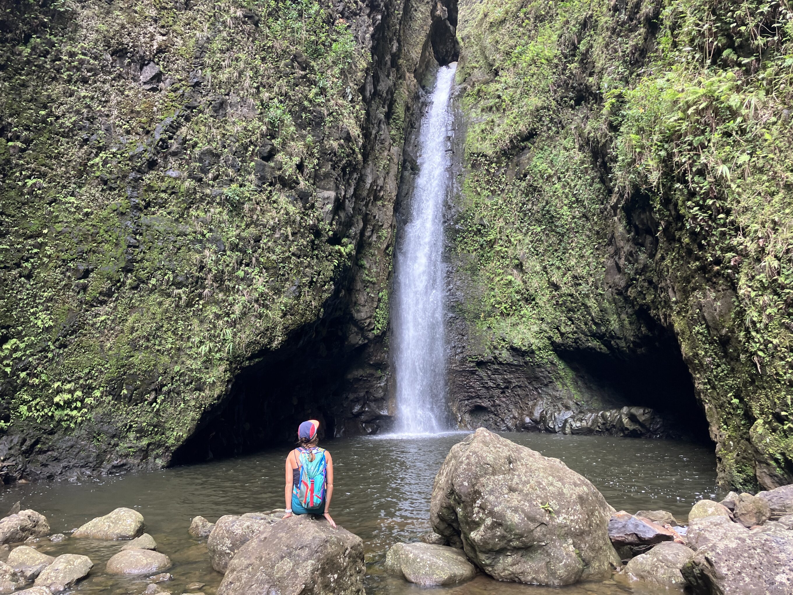 a woman sitting in front of a waterfall