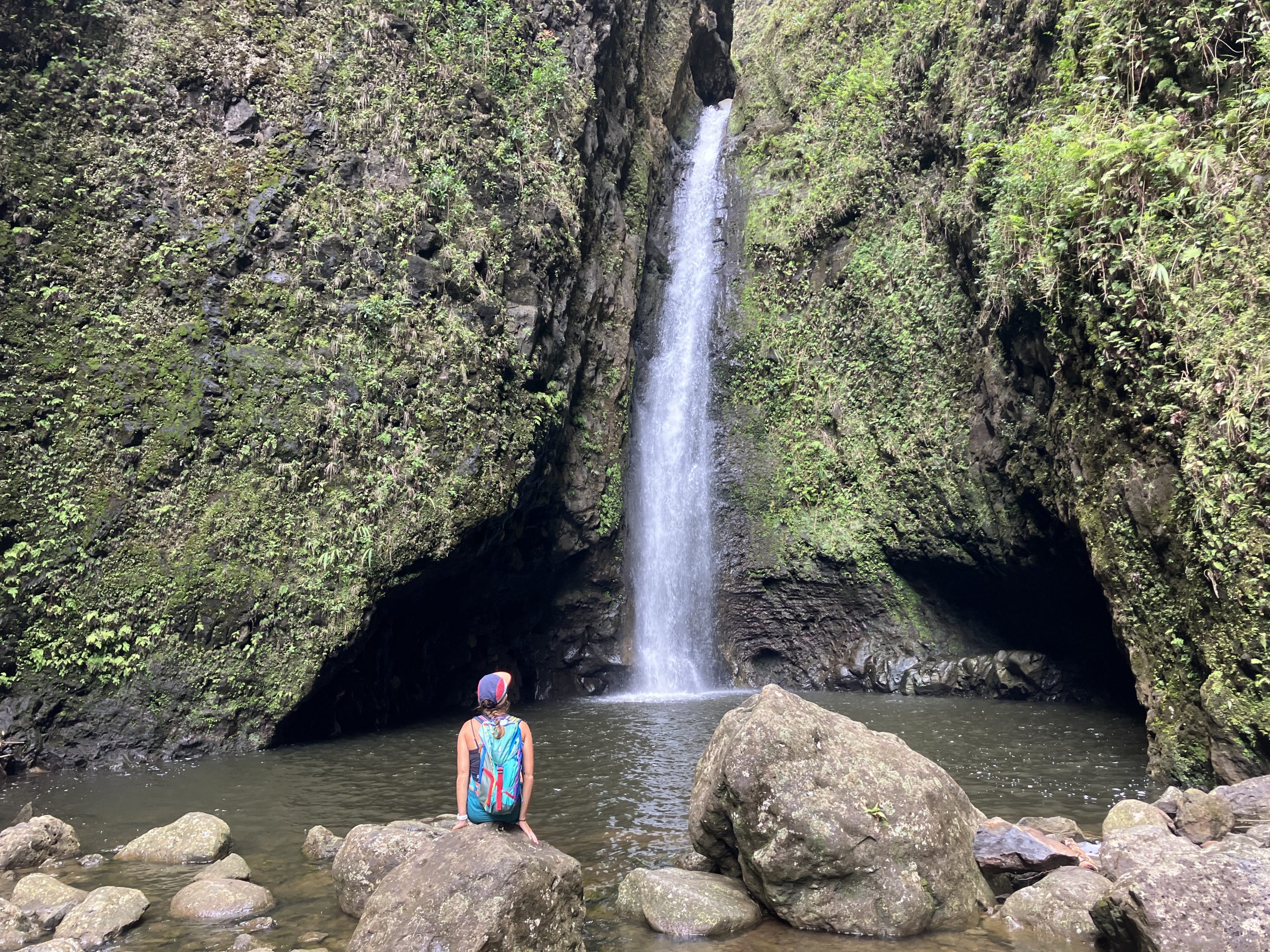 a woman sitting in front of a waterfall