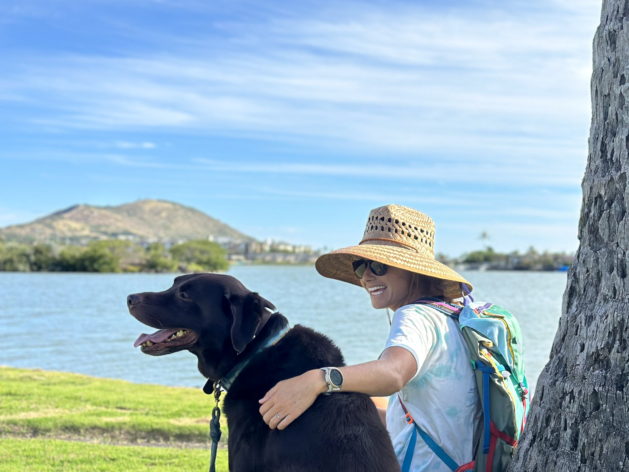 woman wearing a sun hat sitting with a dog