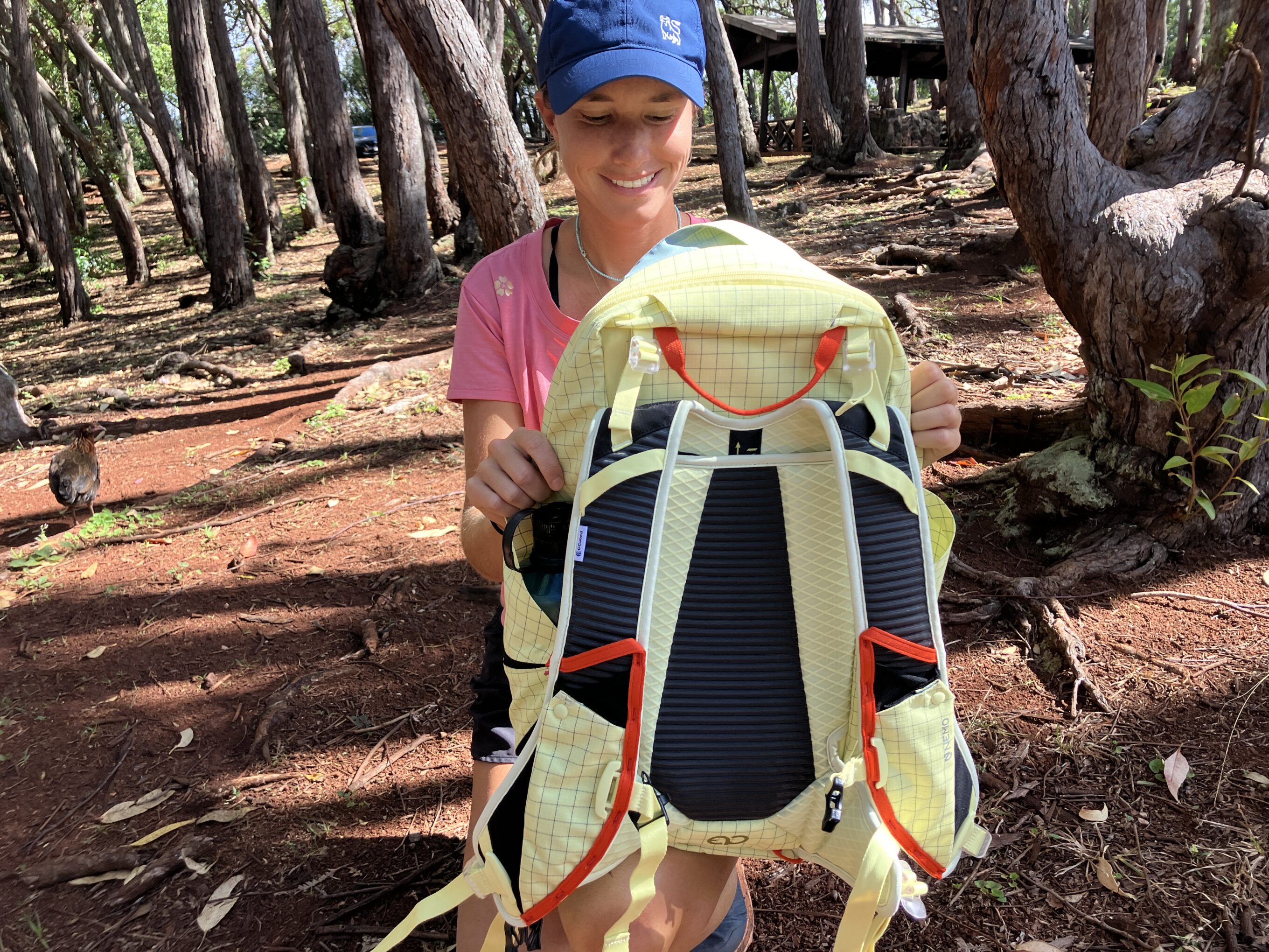 a woman showing the back panel of a hiking backpack