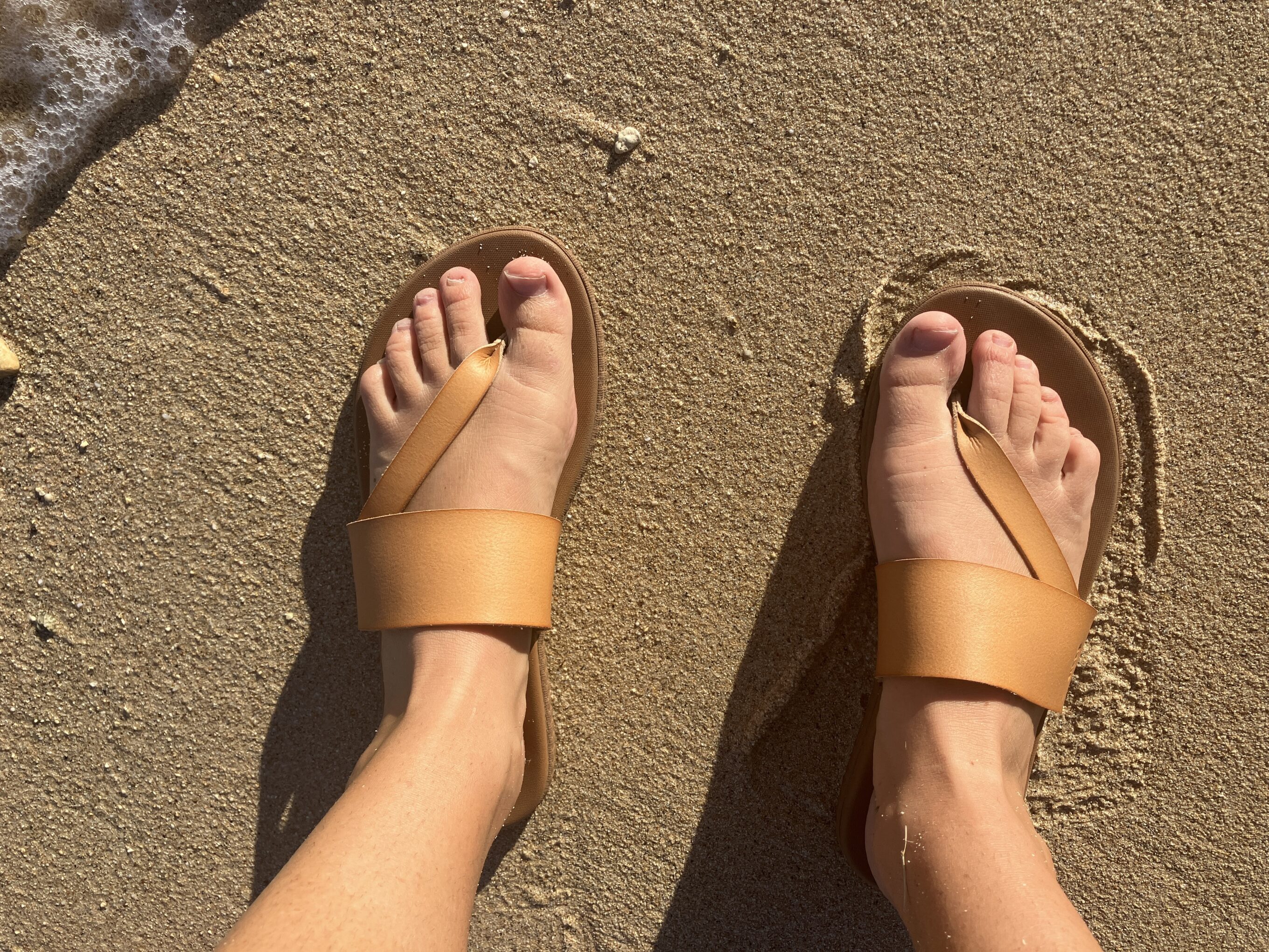 feet in sandals on the beach