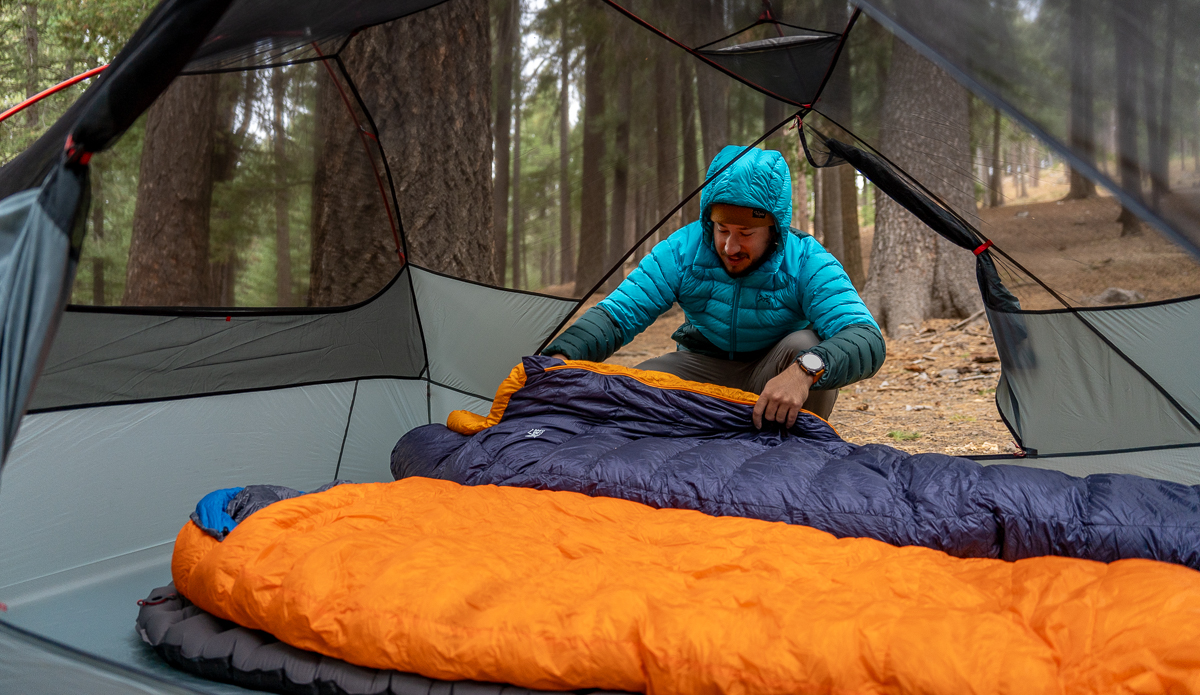 man setting up backpacking sleeping bags in tent