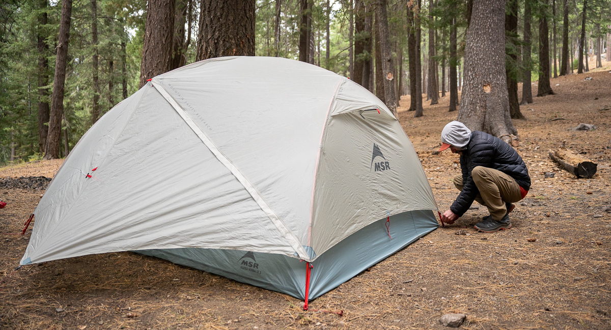 man staking out backpacking tent