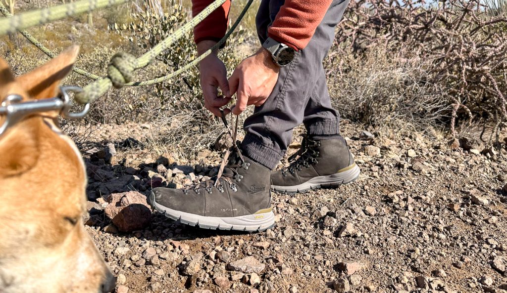 man tying hiking boots on trail